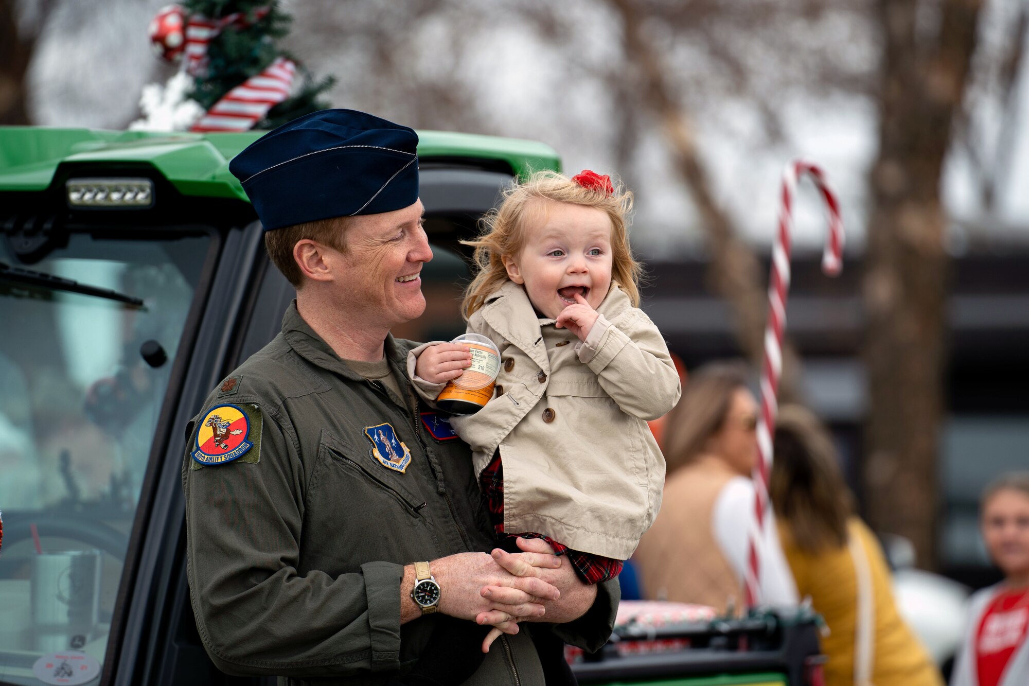 An Airmen holds a little girl in his arms