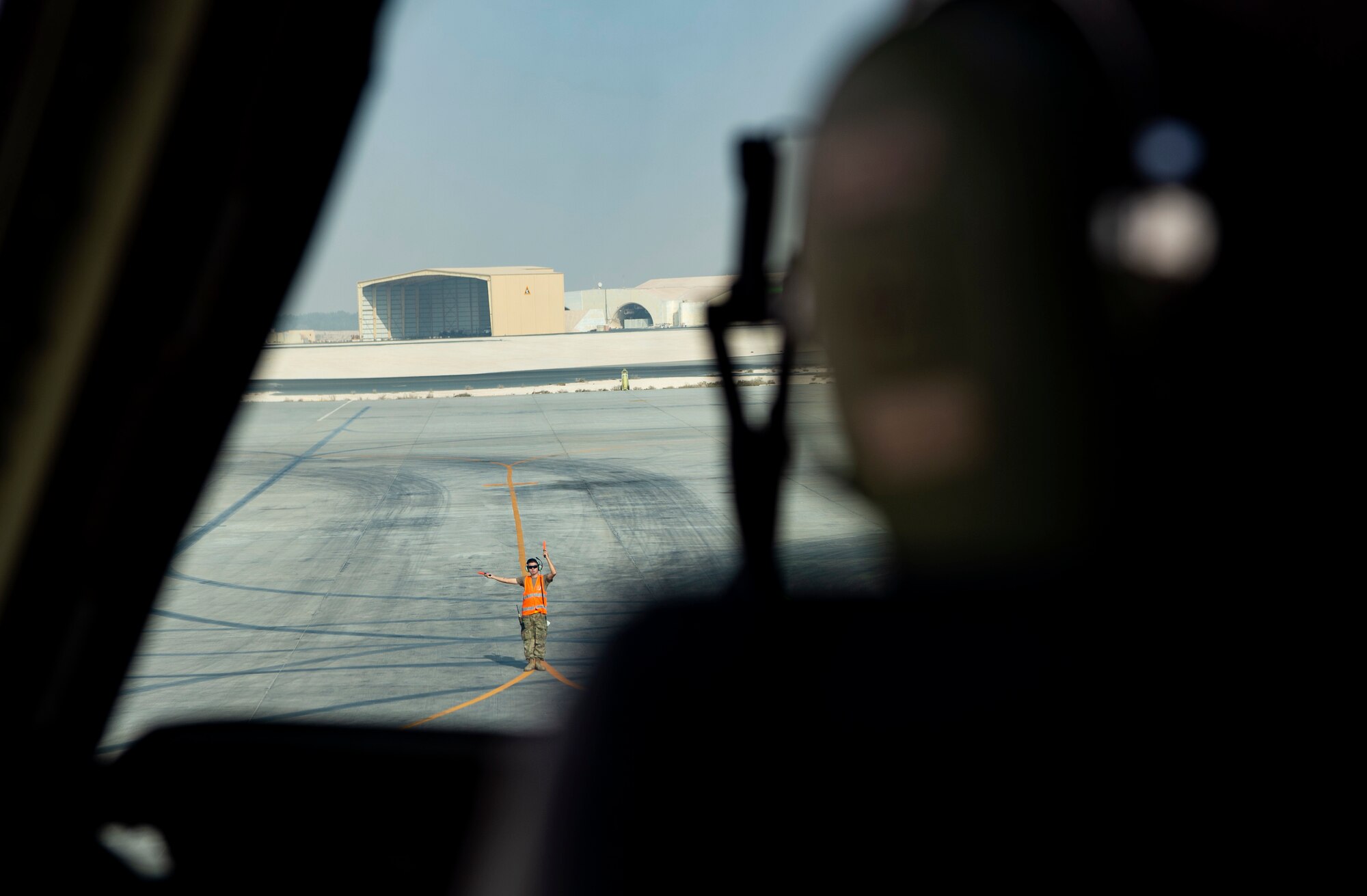 A U.S. Airmen assigned to Al Udeid Air Base, Qatar, left, marshals U.S. Air Force Col. Brian Collins, 62nd Airlift Wing vice commander, to pilot a C-17 Globemaster III out of its parking space at Al Udeid, Dec. 1, 2021. Collins and other 62nd AW Airmen participated in the EAS (Expeditionary Airlift Squadron) Swap Out to deliver deploying Airmen to the 816th EAS at Qatar and bring home those whose deployment had ended. (U.S. Air Force photo by Staff Sgt. Tryphena Mayhugh)