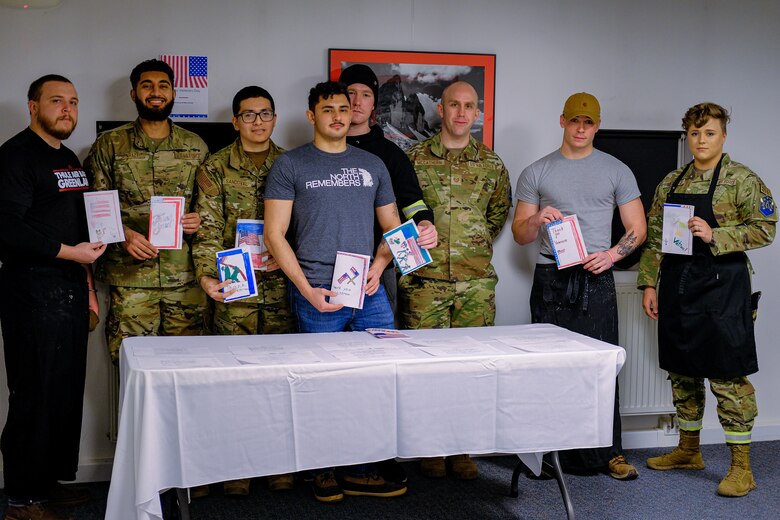 military members stand around holding cards sent to them by 5th grade children in Arizona