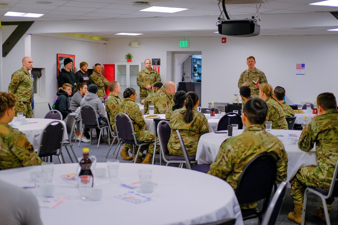 military members gather around to hear a chaplain speak