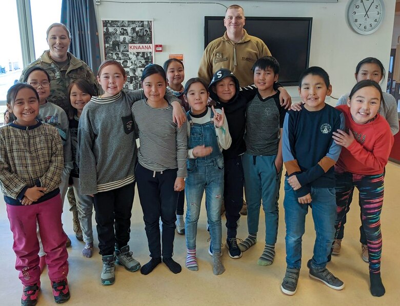 U.S. Air Force Master Sgt. Katherine Anderson and U.S. Air Force Tech. Sgt. Zachary Knowles visit with elementary school children in Quaanaaq, Greenland, Nov. 27, 2021. Anderson and Knowles visited the school principal in preparation for Operation Julemand gift delivery during the holiday season. (U.S. Air Force courtesy photo)