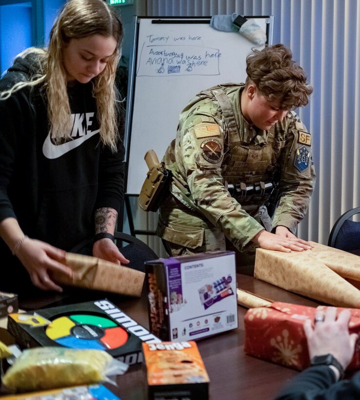 U.S. Air Force Airman 1st Class Emma Weaver, 821st Security Forces Squadron Defender, and U.S. Air Force Senior Airman Nevaeh Steinmetz, 821st SFS Defender, work together to wrap a table filled with gifts for Greenlandic school children at Thule Air Base, Greenland, Nov. 6, 2021. These gifts will be delivered to nearby villages for the holidays as part of Operation Julemand. (U.S. Air Force photo by Staff Sgt. David Svendsen)