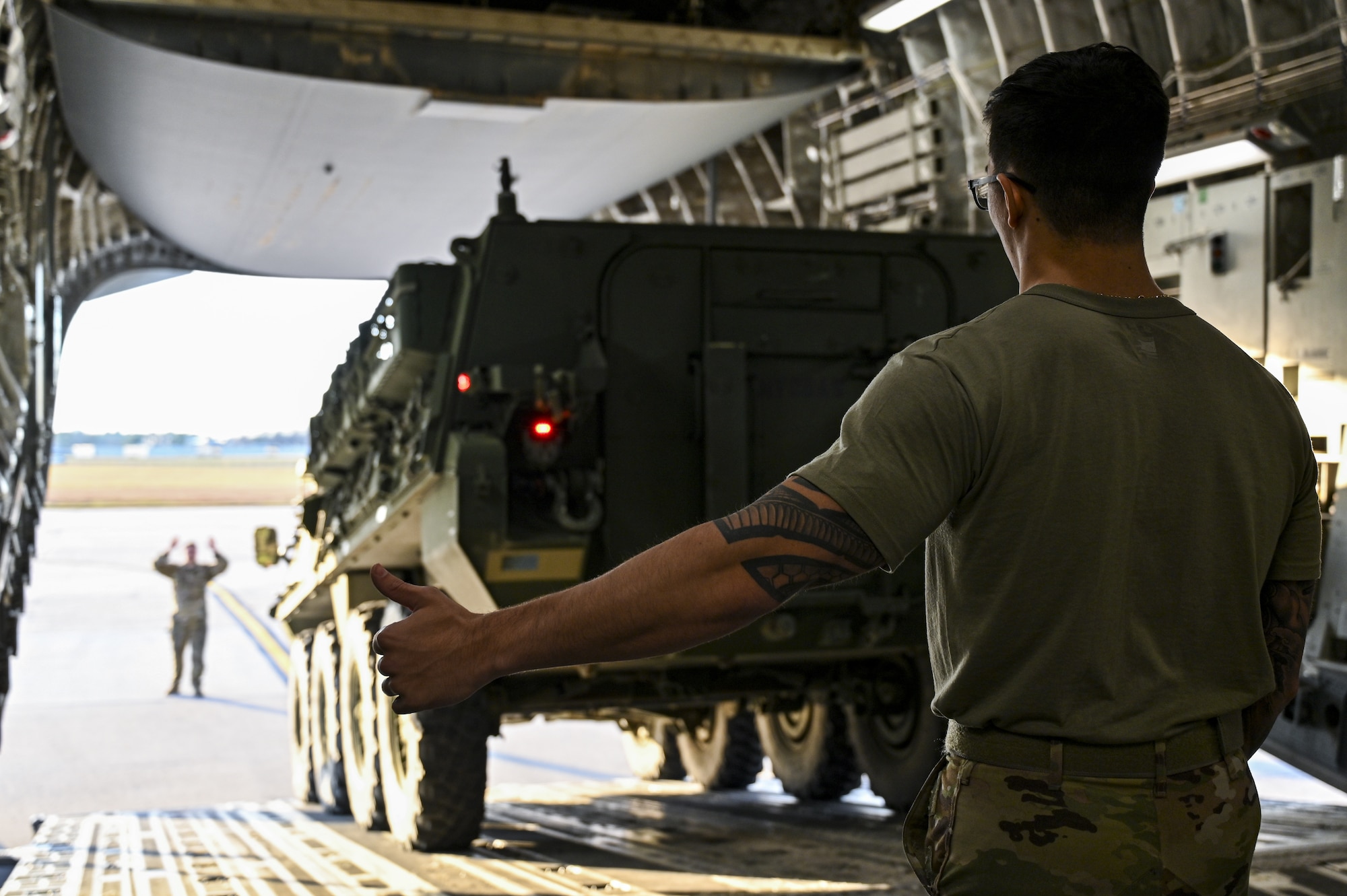 U.S. Air Force Senior Airman Joseph Vieira (font) and Airman 1st Class Christian Downing (back), 6th Airlift Squadron, loadmaster, direct the upload of an M1126 STRYKER onto a C-17 Globemaster III on Dec. 7, 2021, at Joint Base McGuire-Dix-Lakehurst, N.J. The 621st and 321st Contingency Response Squadrons along with the 6th Airlift Squadron and U.S. Army C5ISR Ground Activity, participated in a joint service exercise. Joint inspection qualifications were accomplished by Airmen who uploaded two M1126 STRYKER vehicles onto a C-17 Globemaster III. The airframe with cargo then performed multiple touch-and-goes at Naval Support Activity Lakehurst before returning to McGuire Air Force Base.