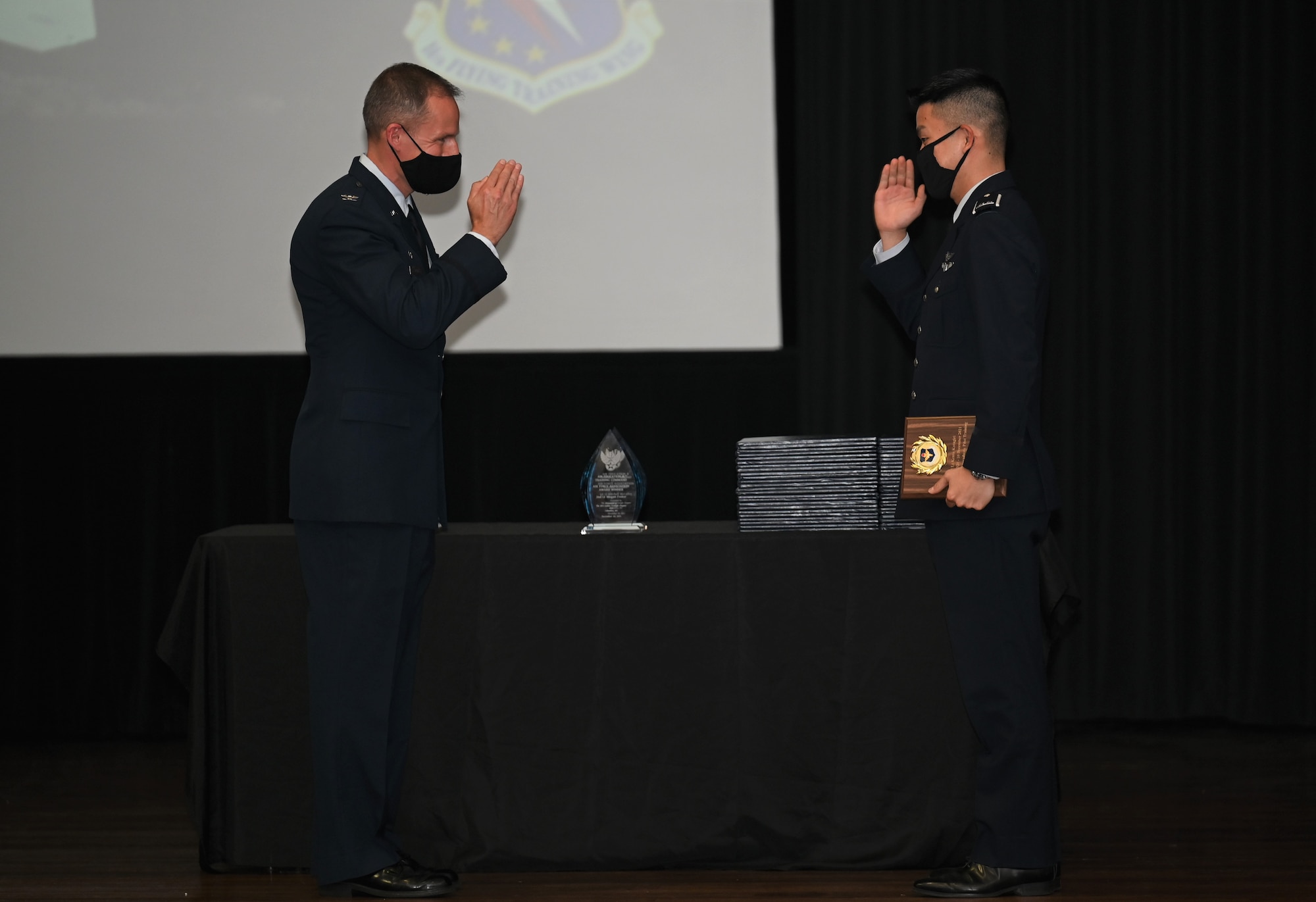 U.S. Air Force Col. Justin Spears, 14th Operations Group commander, returns a salute to Japan Air Self-Defense Force 1st Lt. Kento Katagiri, after presenting him with an International Training Award, Dec. 10, 2021, on Columbus Air Force Base, Miss. Specialized Undergraduate Pilot Training class 22-03 graduated pilots from Japan, Saudi Arabia and Republic of Turkey. (U.S. Air Force photo by Airman 1st Class Jessica Haynie)