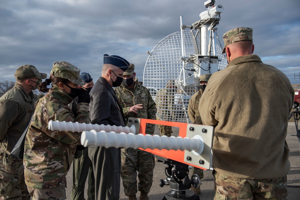 a group of airmen discuss new radar innovations, two radars are displayed