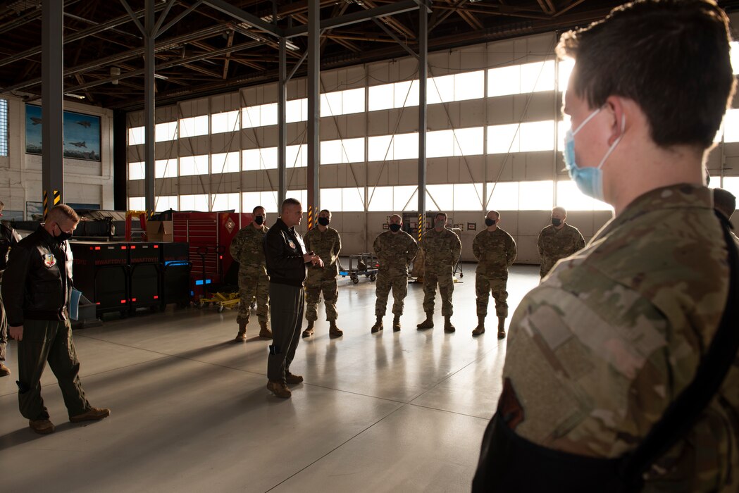 A group of Airmen stand in a hangar having a discussion with Maj. Gen. Michael G. Koscheski