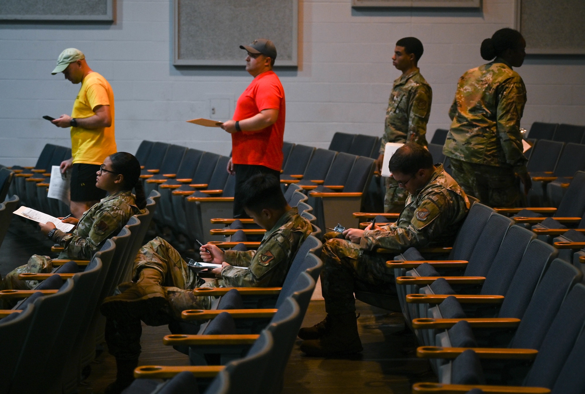 Department of the Air Force personnel wait in line and complete an Air Force Form 594 at the Hickam Memorial Theater at Joint Base Pearl Harbor-Hickam, Hawaii, Dec. 8, 2021. Service members must provide a physical copy of proof of residence to the Temporary Lodging Allowance Meal Rate Claim Processing Center line to ensure eligibility. TLA is available for Department of the Air Force personnel choosing to remain in their JBPHH residence during the current water issues. The center is open for processing from 1:00 - 5:00 p.m. on Dec. 8 - 10. (U.S. Air Force photo by Staff Sgt. Alan Ricker)