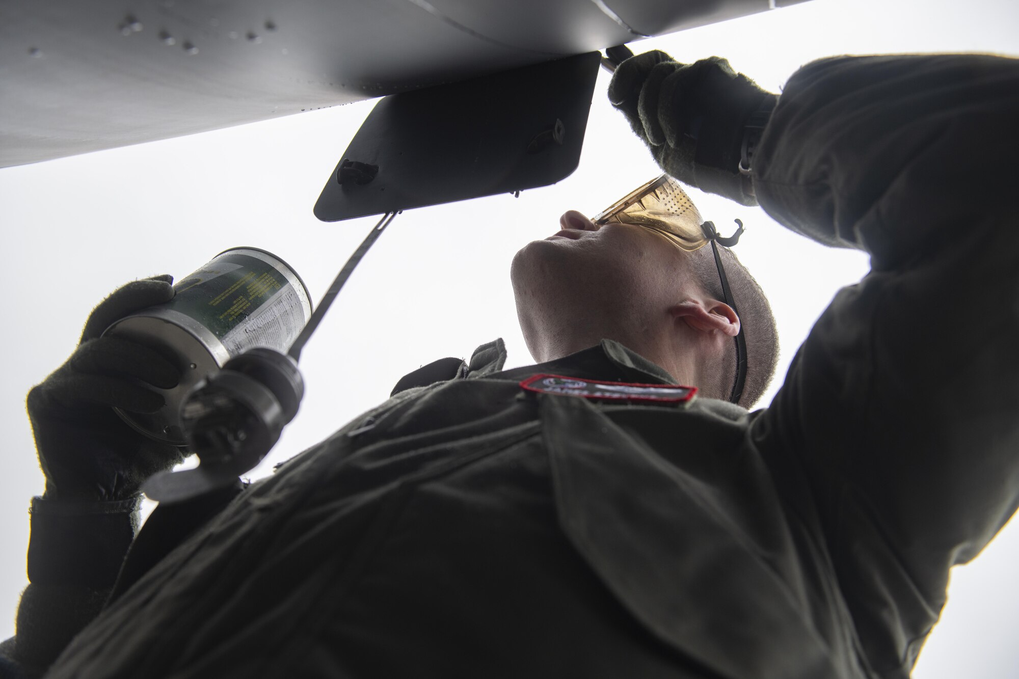 U.S. Air Force 1st Lt. James Stevens, 92nd Air Refueling Squadron KC-135 Stratotanker pilot, services a KC-135 with hydraulic fluid during a large-scale readiness exercise at Joint Base Lewis-McChord, Washington, Dec. 7, 2021. Multiple crews from Fairchild Air Force Base flew to various locations to train and exercise multi-capable Airmen concepts, such as aircrew Airmen performing routine maintenance tasks on the KC-135. (U.S. Air Force photo by Staff Sgt. Lawrence Sena)