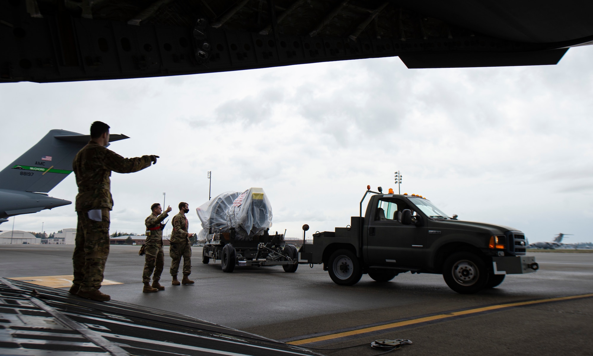 U.S. Air Force Senior Airman Peter Siviglia, 4th Airlift Squadron loadmaster, marshals a C-17 Globemaster III jet engine onto a C-17 at Joint Base Lewis-McChord, Washington, Nov. 27, 2021. The jet engine was being delivered to Joint Base McGuire-Dix-Lakehurst, New Jersey, during the 816th Expeditionary Airlift Squadron deployment swap out at Al Udeid Air Base, Qatar. (U.S. Air Force photo by Staff Sgt. Tryphena Mayhugh)