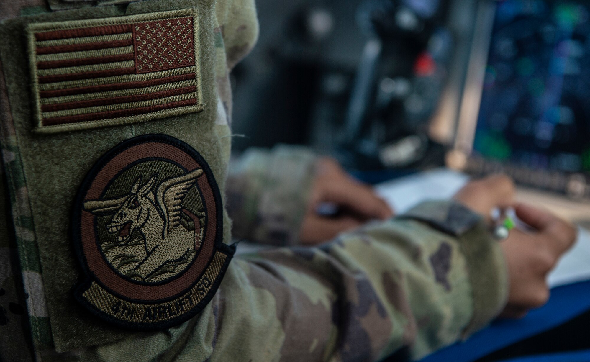 U.S. Air Force 1st Lt. Erica Drakes, 4th Airlift Squadron pilot, takes notes while piloting a C-17 Globemaster III to deliver deploying Airmen to Al Udeid Air Base, Qatar, Nov. 28, 2021. Several times a year, Airmen assigned Joint Base Lewis-McChord, Washington, and other Air Mobility Command C-17 bases deploy to Al Udeid for airlift operations in countries such as Afghanistan, Iraq, Iran and more. (U.S. Air Force photo by Staff Sgt. Tryphena Mayhugh)