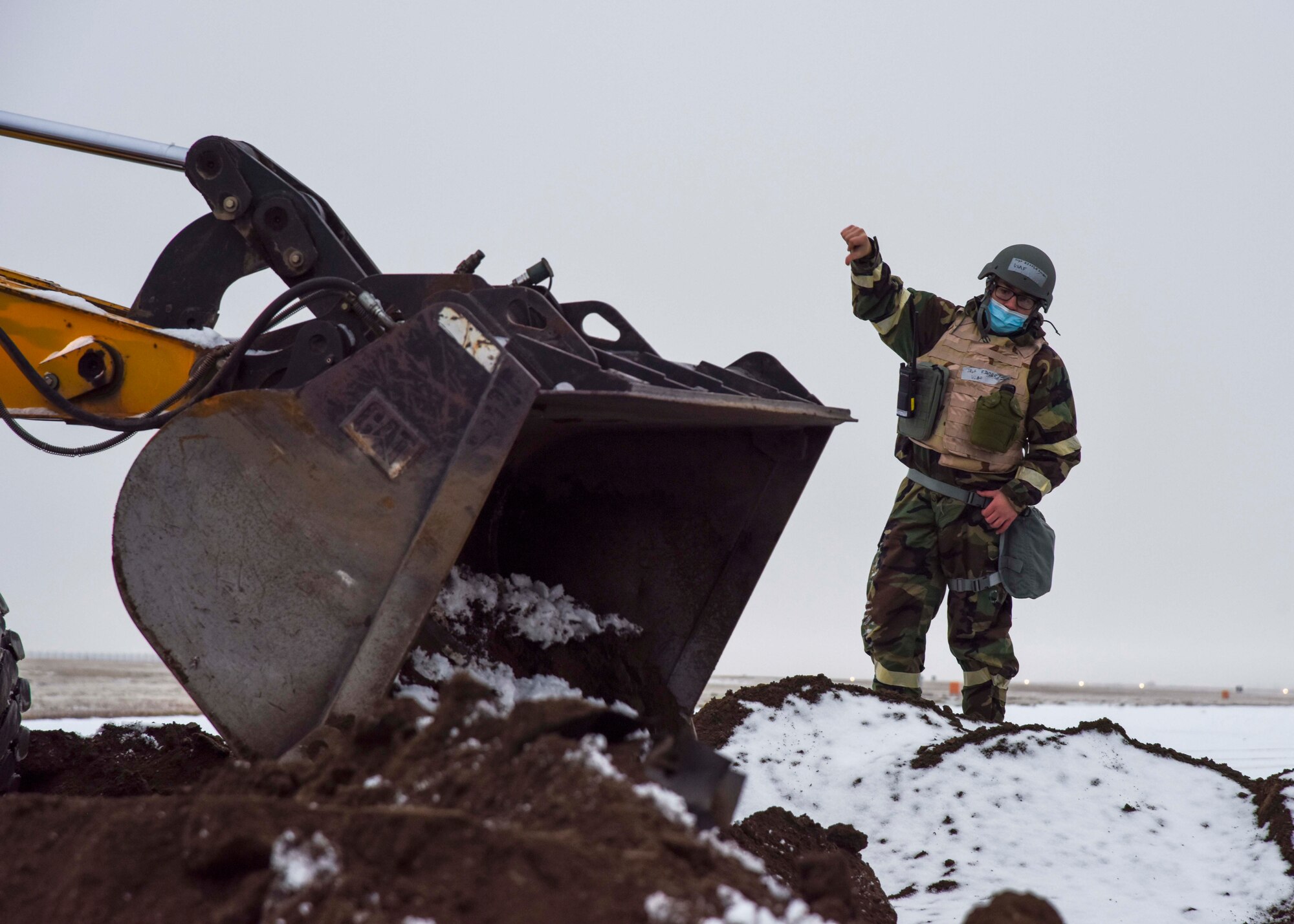 U.S. Air Force Staff Sgt. Brendan Kinser, 92nd Civil Engineer Squadron equipment operator, instructs his wingman on filling a hole on the flightline as part of the large-scale readiness exercise at Fairchild Air Force Base, Washington, Dec. 7, 2021. Training exercises, such as this LRE, are critically important to ensuring the readiness of Airmen and validates the wing’s constant readiness to deliver rapid global mobility. (U.S. Air Force photo by Airman 1st Class Anneliese Kaiser)