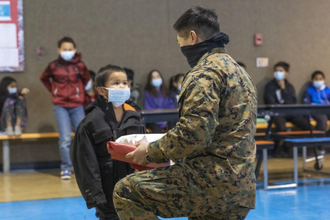 U.S. Marine Corps Sgt. Richard Park, a canvasing recruiter with Recruiting Sub-Station Wasilla, Recruiting Station Portland, gives a gift to a child during a Toys for Tots event at Top of the Kuskokwim School, Nikolai, Alaska on Dec 3, 2021. Park wanted to give back to the community by assisting the Marine Corps Reserves with their annual Toys for Tots program. Marines and Airmen traveled to remote villages of Alaska’s Kuskokwim Valley in support of the Marine Corps Reserve’s Toys for Tots. (U.S. Marine Corps photo by Staff Sgt. Kelsey Dornfeld)