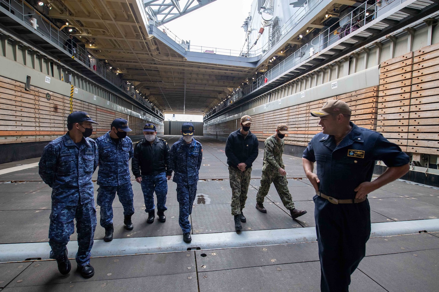 Cmdr. Bryan Gallant, the executive officer aboard the forward-deployed amphibious dock landing ship USS Rushmore (LSD 47), conducts a tour of the ship’s well deck for allies from the Japan Maritime Self-Defense Force. Rushmore, part of Amphibious Squadron 11, is operating in the U.S. 7th Fleet area of responsibility to enhance interoperability with allies and partners and serve as a ready response force to defend peace and stability in the Indo-Pacific region.