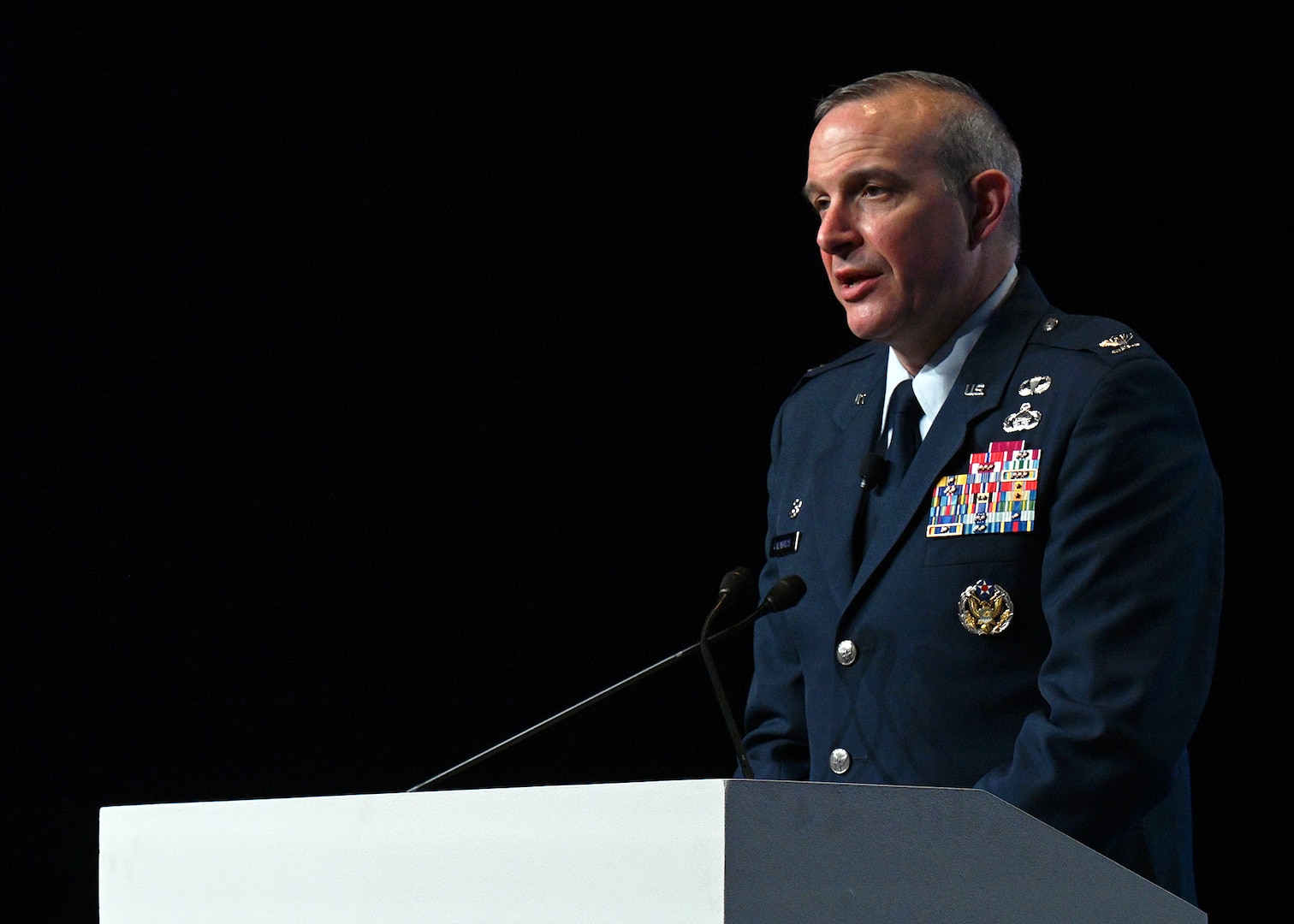 Image of person on stage behind a podium, presenting to an audience.