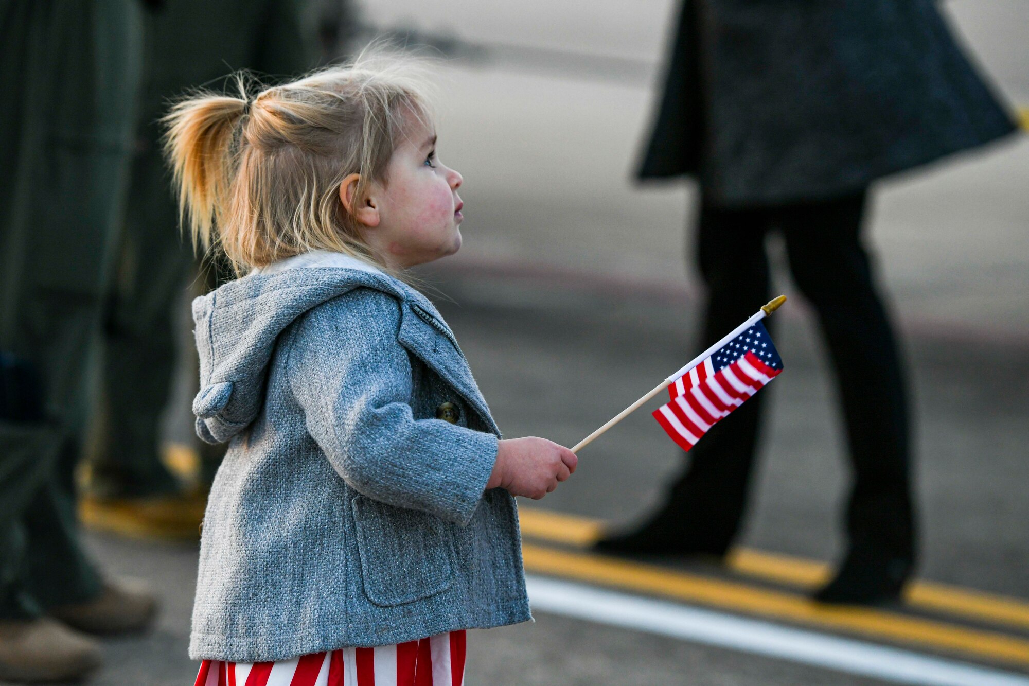 An Airman's daughter waves a flag.