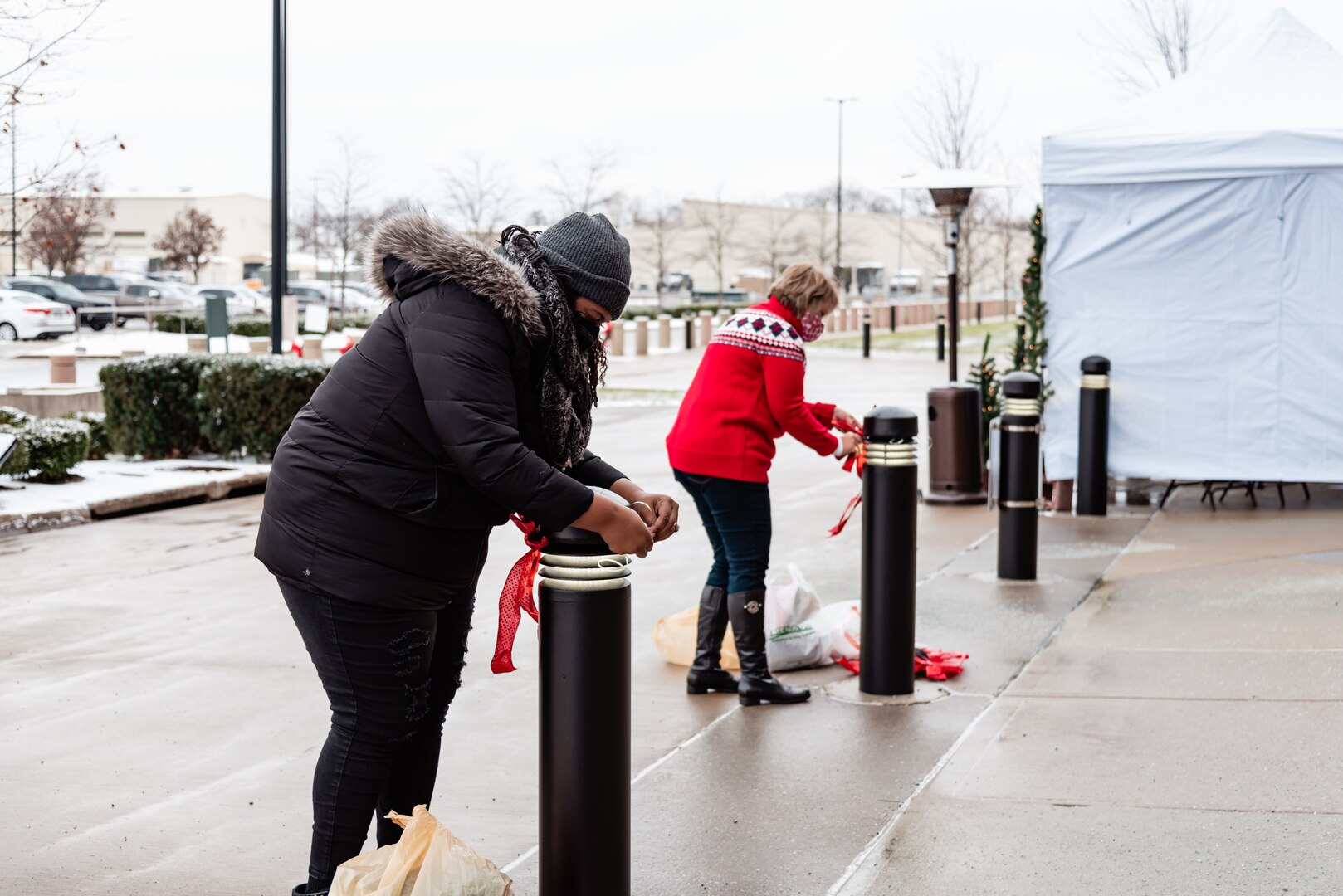 Two women decorate the bollards outside Building 20.