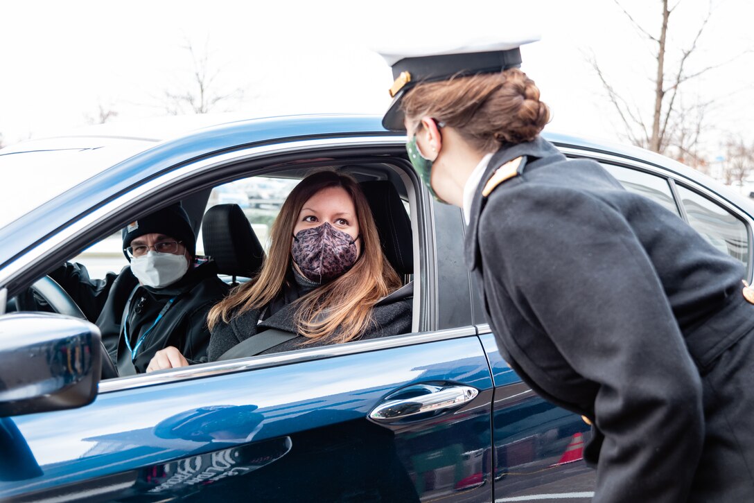 DLA Land and Maritime Commander Navy Rear Adm. Kristen Fabry speaks with a woman in a car.