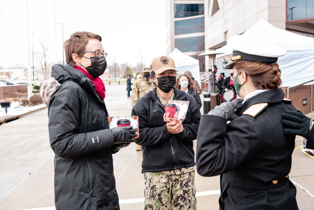 DLA Land and Maritime Commander Navy Rear Adm. Kristen Fabry speaks with a woman in military uniform and a woman in a coat.