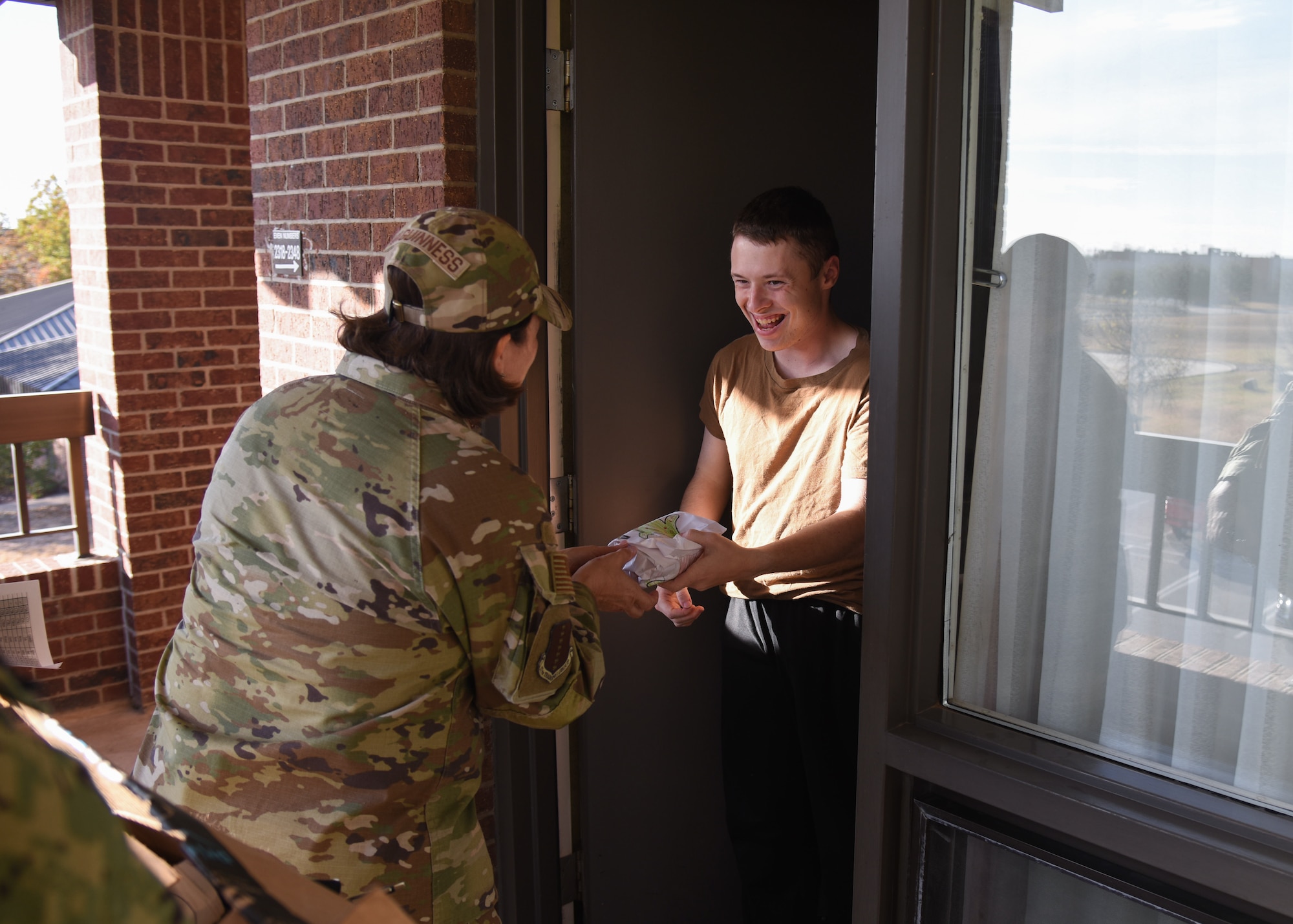 U.S. Air Force Col. Angelina Maguinness, 17t Training Group commander, hands a bag of cookies to a dorm resident during the Cookie Caper event, Dec. 10, 2021, on Goodfellow Air Force Base, Texas. This event is focused on delivering holiday cheer to students and permanent party residing in the dorms. (U.S. Air Force photo by Staff Sgt. Tyrell Hall)