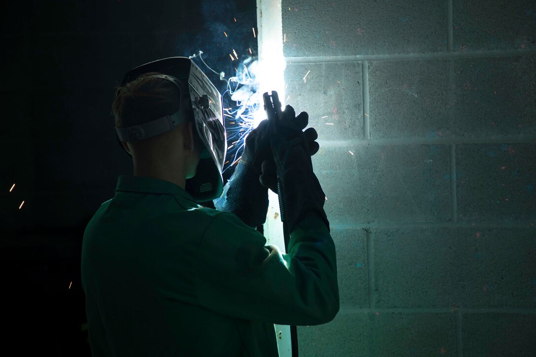 Sparks fly as a Marine welds a door.