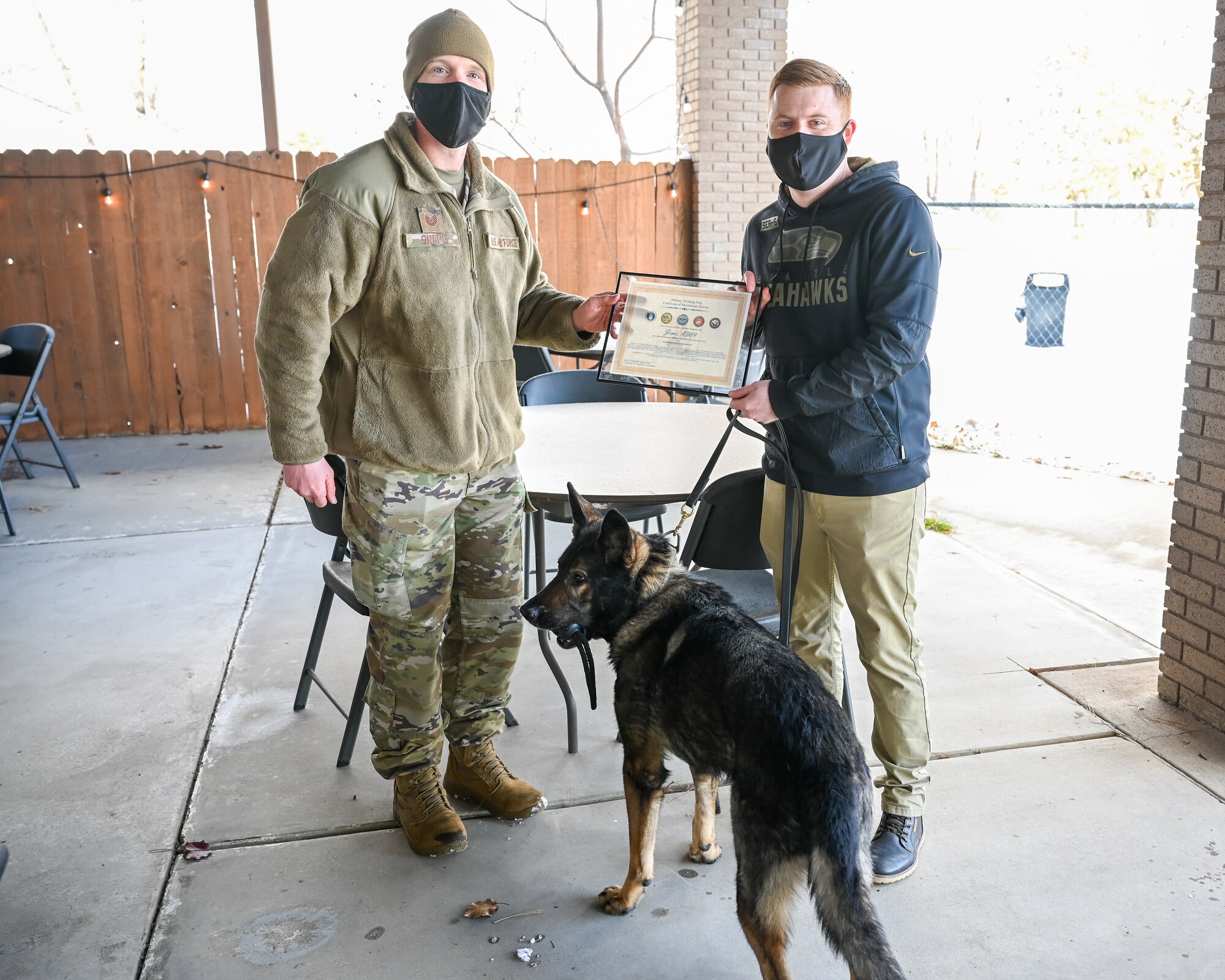 Military working dog Jimo with former handler Staff Sgt. Patrick Cushing (right), 75th Security Forces Squadron, is recognized during his retirement celebration by Tech. Sgt. Kyle Snape, 75th SFS MWD NCOIC, Dec. 10, 2021, at Hill Air Force Base, Utah. MWD Jimo retired honorably after serving six years with the 75th SFS at Hill. (U.S. Air Force photo by Cynthia Griggs)