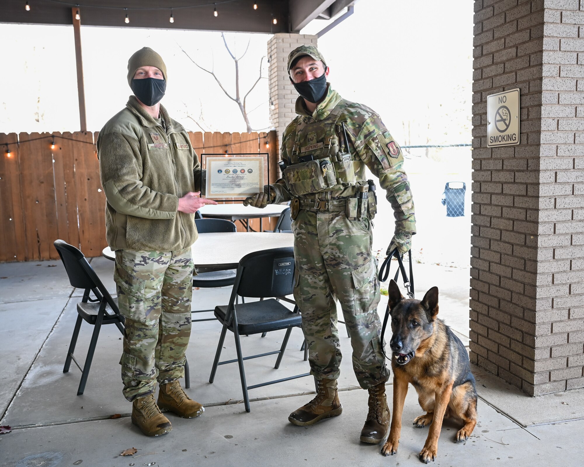 Military working dog Bastas with former handler Staff Sgt. Tyler Hopkins (right), 75th Security Forces Squadron, is recognized during his retirement celebration by Tech. Sgt. Kyle Snape, 75th SFS MWD NCOIC, Dec. 10, 2021, at Hill Air Force Base, Utah. MWD Bastas retired honorably after serving six years with the 75th SFS at Hill. (U.S. Air Force photo by Cynthia Griggs)