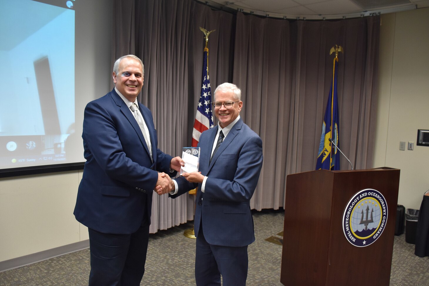 Dr. William Burnett, Technical Director, Naval Meteorology and Oceanography Command (CNMOC), presents Mr. David Brazier with a graduation award at the FY2020 CNMOC Executive Leadership Program graduation ceremony at Stennis Space Center, MS, Nov. 19, 2021. CNMOC directs and oversees more than 2,500 globally-distributed military and civilian personnel who collect, process and exploit environmental information to assist Fleet and Joint Commanders in all warfare areas to make better decisions faster than the adversary.