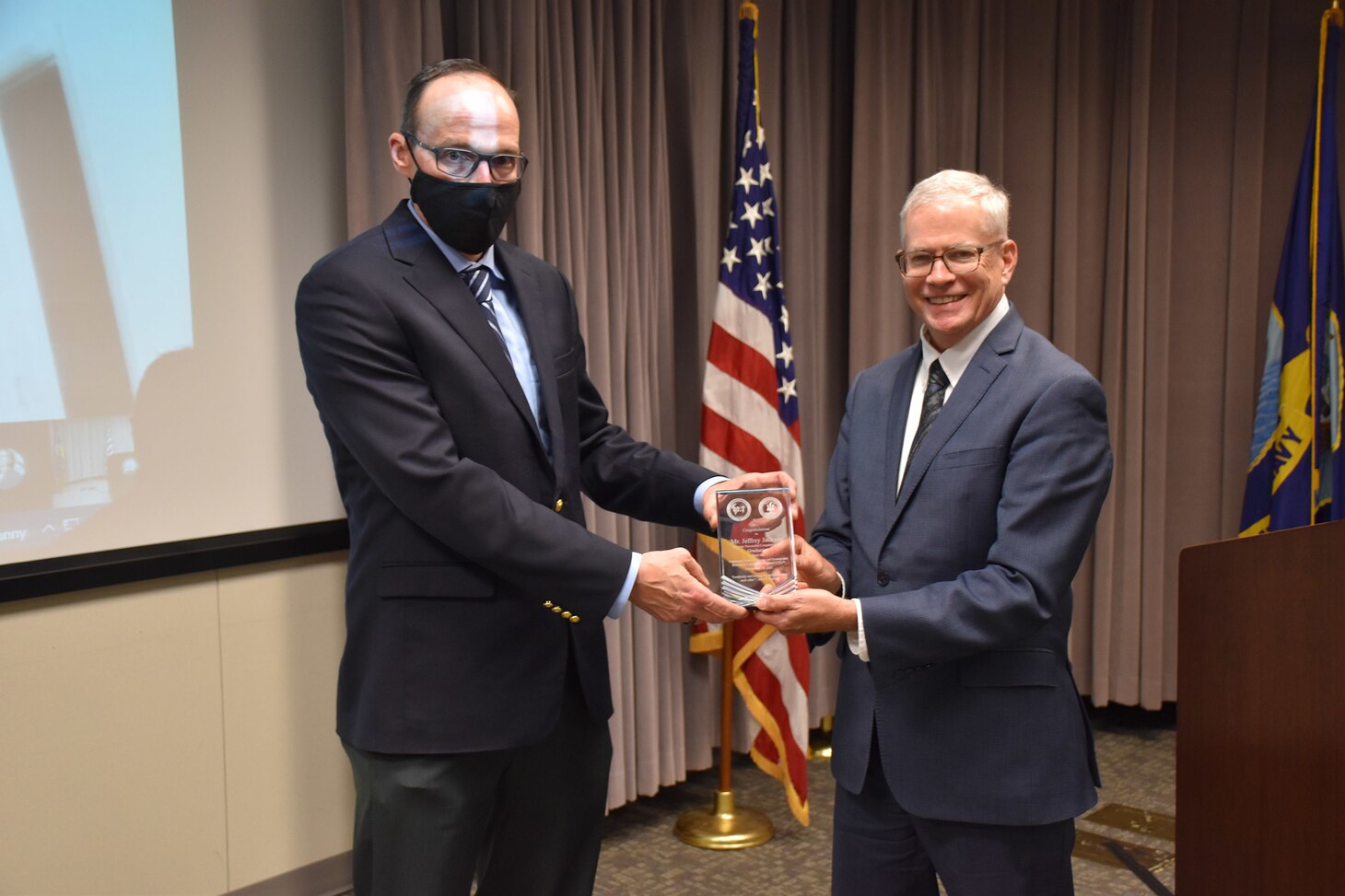 Dr. William Burnett, Technical Director, Naval Meteorology and Oceanography Command (CNMOC), presents Mr. Jeffrey Jackson, Fleet Weather Center and CELP graduate, with a graduation award at the FY2020 CNMOC Executive Leadership Program graduation ceremony at Stennis Space Center, MS, Nov. 19, 2021. CNMOC directs and oversees more than 2,500 globally-distributed military and civilian personnel who collect, process and exploit environmental information to assist Fleet and Joint Commanders in all warfare areas to make better decisions faster than the adversary.