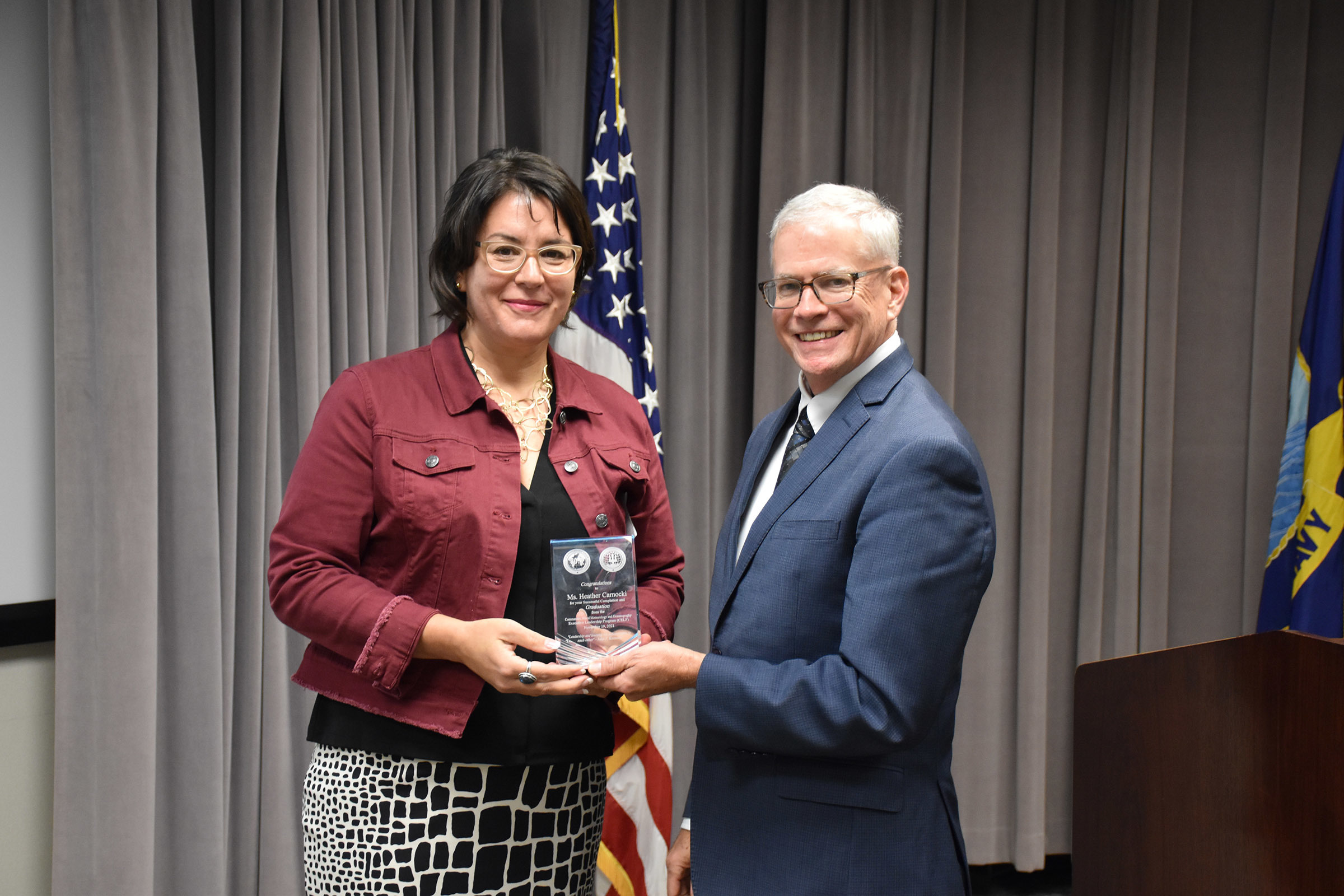 Dr. William Burnett, Technical Director, Naval Meteorology and Oceanography Command (CNMOC), presents Ms. Heather Carnocki with a graduation award at the FY2020 CNMOC Executive Leadership Program graduation ceremony at Stennis Space Center, MS, Nov. 19, 2021. CNMOC directs and oversees more than 2,500 globally-distributed military and civilian personnel who collect, process and exploit environmental information to assist Fleet and Joint Commanders in all warfare areas to make better decisions faster than the adversary.