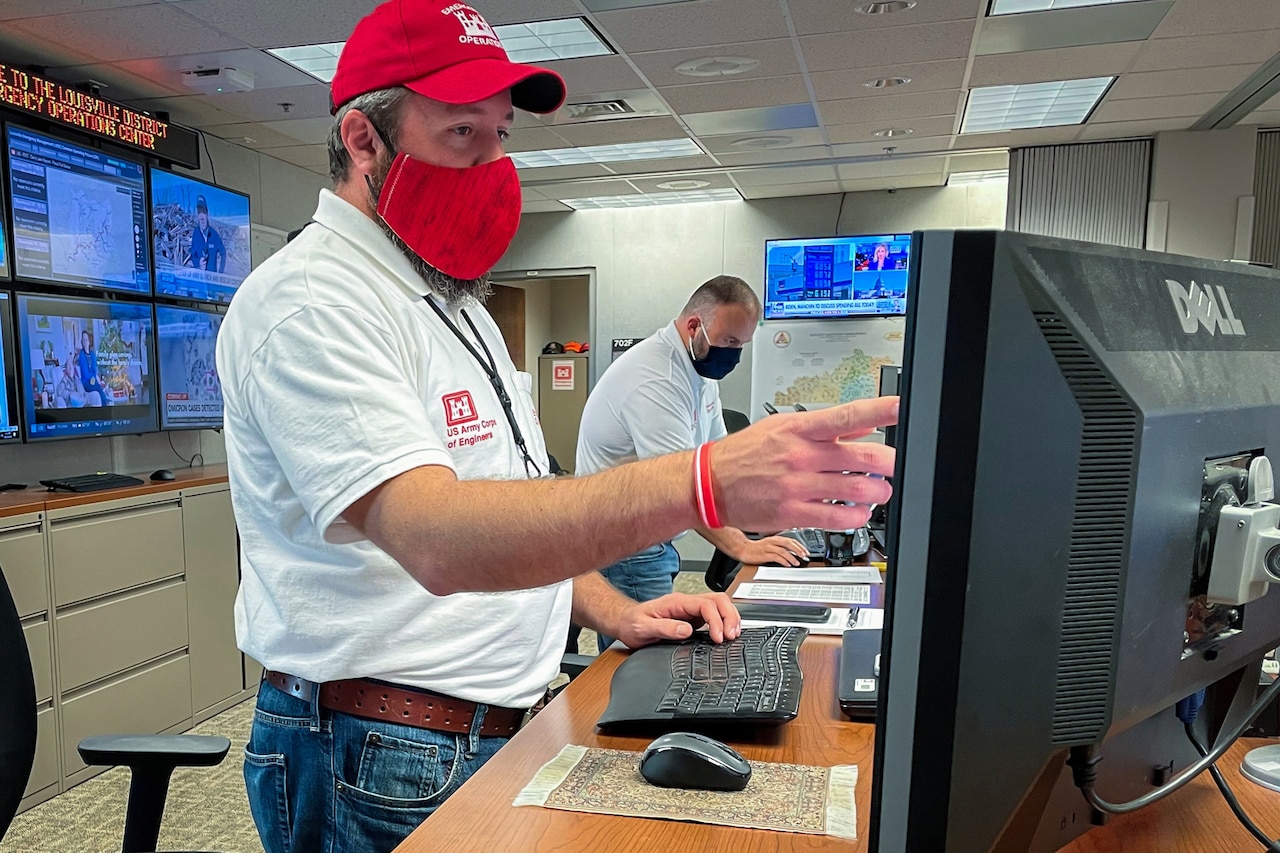 Men operate computers.