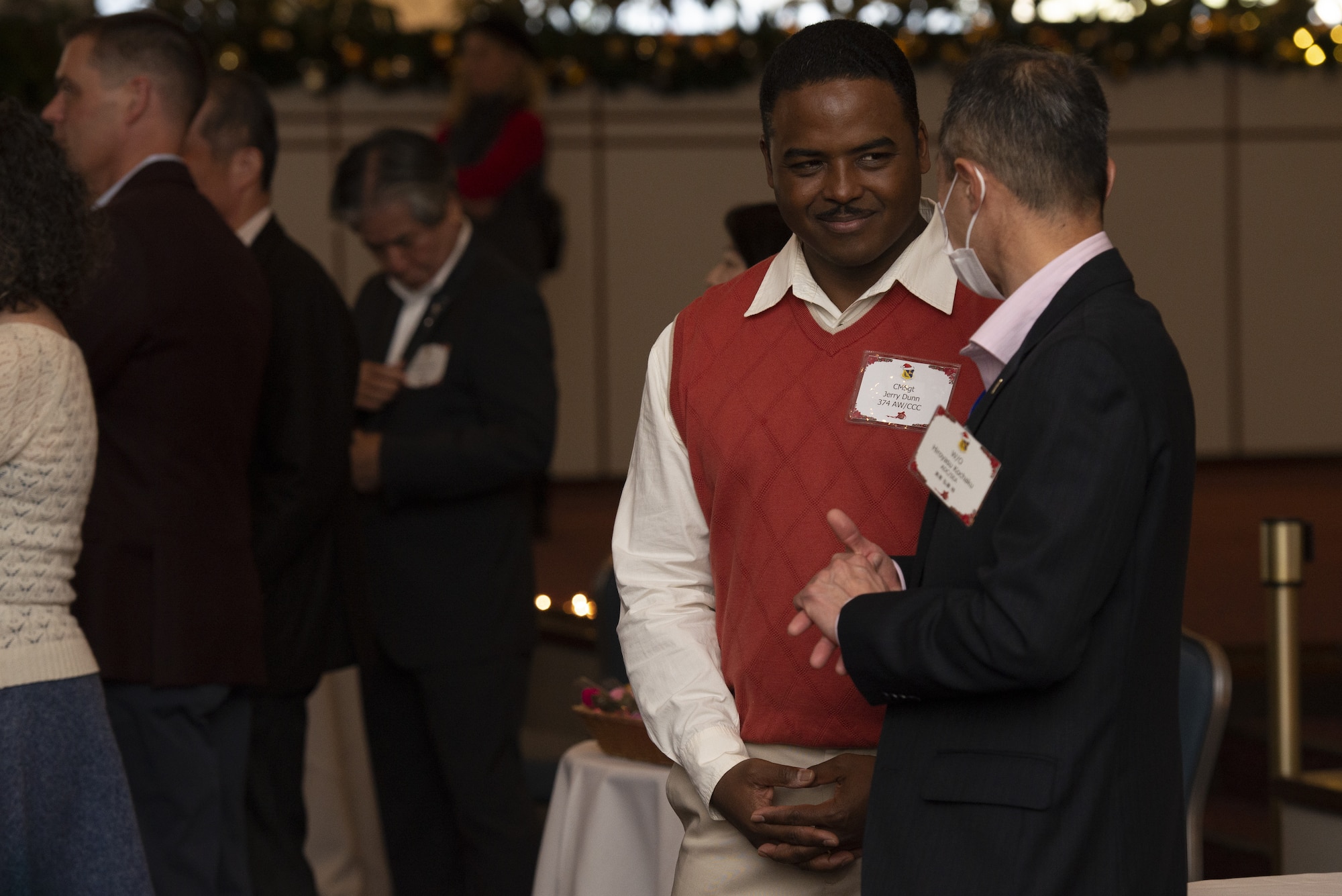 Chief Master Sgt. Jerry Dunn, 374th Airlift Wing command chief, center, talks to Warrant Officer Hiroyasu Kochaku, Japan Air Self Defense Force Air Defense Command senior enlisted advisor, during the 374th AW Holiday Social at the Yokota Officers Club at Yokota Air Base, Japan, Dec. 11, 2021. The event was an opportunity for wing leadership and Japanese partners from the JASDF, Japan America Air Force Goodwill Association, friendship clubs, and Government of Japan, to celebrate the holiday season together. Attendees were able to strengthen their relationships while enjoying live music performed by the Yokota High School and a children’s ballet dance. (U.S. Air Force photo by Tech. Sgt. Christopher Hubenthal)