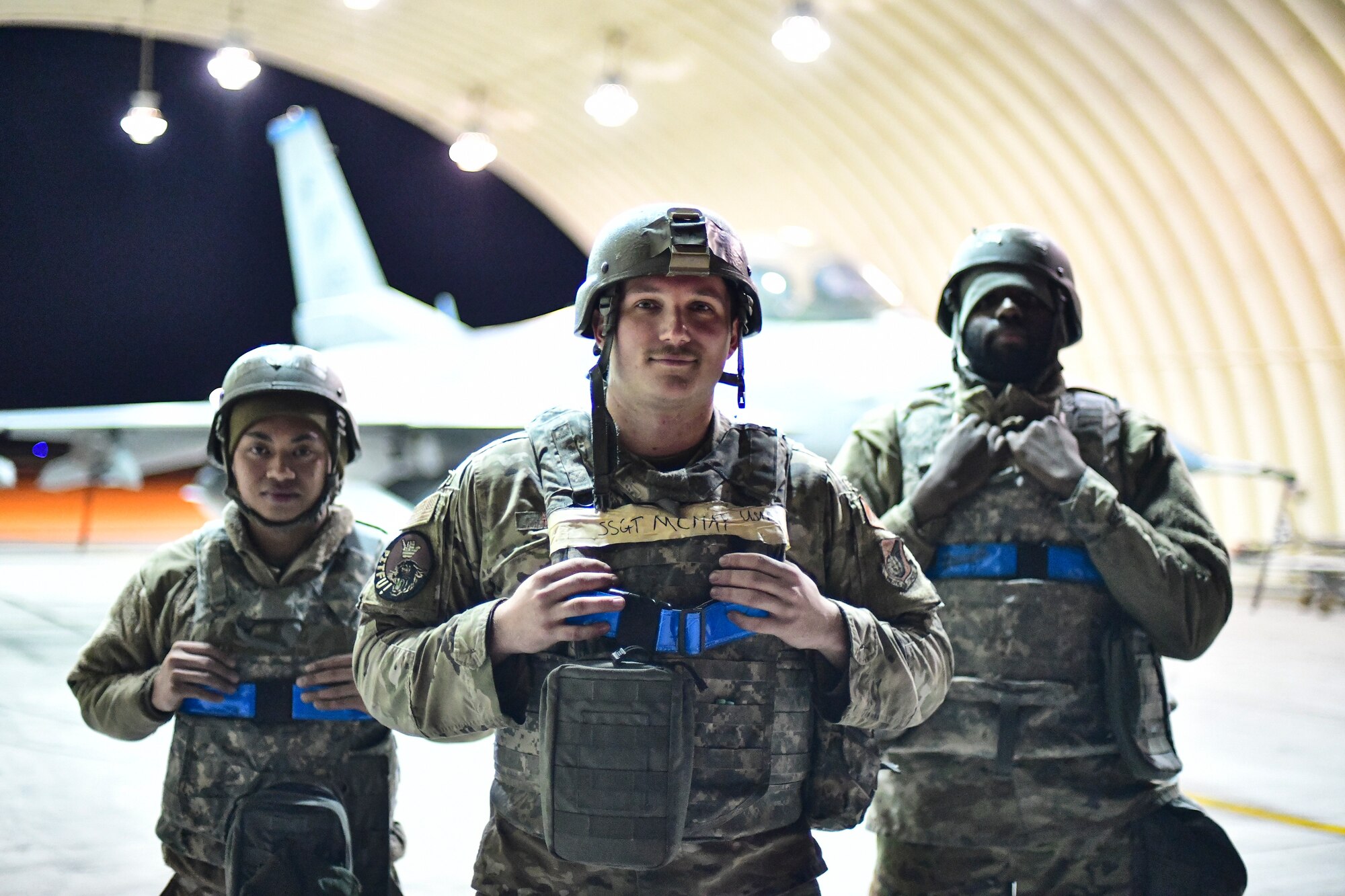 Airmen stand together under a hangar.