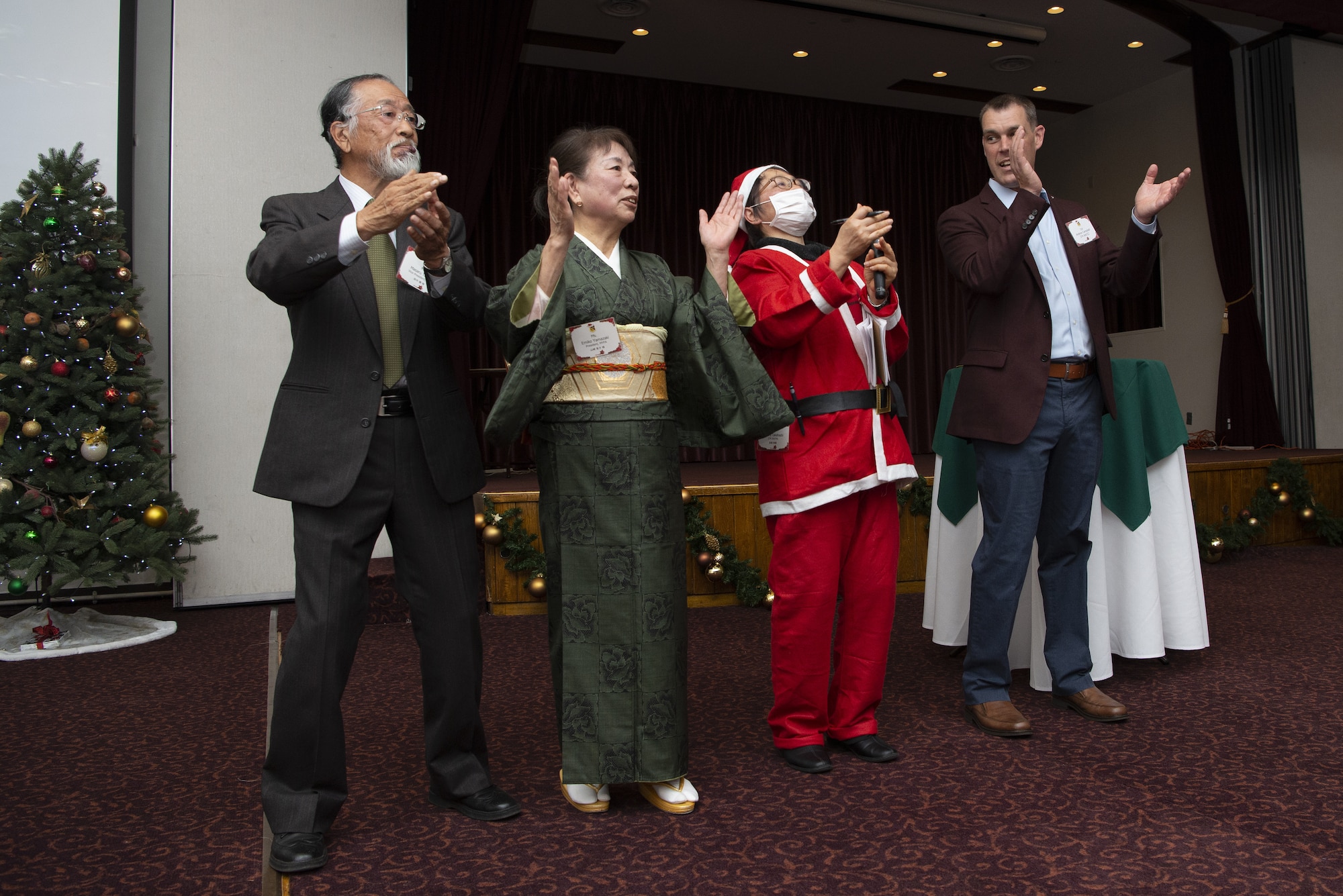 Col. Andrew Campbell, right, 374th Airlift Wing commander, closes out the 374th AW Holiday Party with Masaru Tanaka, left, Mizuho Yokota Friendship Association vice president, Emiko Yamazaki, center left, MYFA president, and Mitsuru Takahashi, center right, 374th AW public affairs community relations specialist, at the end of the 374th AW Holiday Social at the Yokota Officers Club at Yokota Air Base, Japan, Dec. 11, 2021. The event was an opportunity for wing leadership and Japanese partners from the Japan Air Self Defense Forces, Japan America Air Force Goodwill Association, friendship clubs, and Government of Japan, to celebrate the holiday season together. Attendees were able to strengthen their relationship while enjoying live music performed by the Yokota High School and a children’s ballet dance. (U.S. Air Force photo by Tech. Sgt. Christopher Hubenthal)