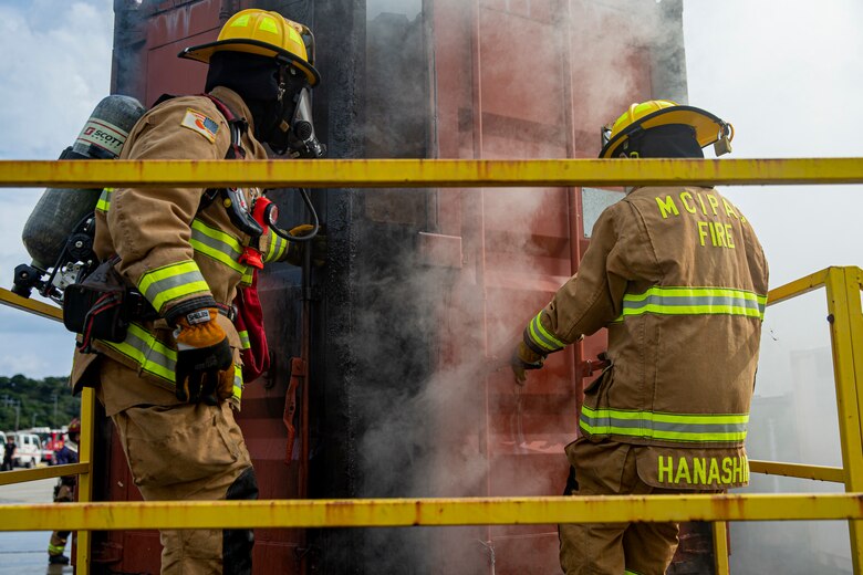 Firefighters with Marine Corps Installations Pacific Fire and Emergency Services open the hatches of a Swede Survival Phase 1 System to extinguish a fire during live-fire flashover training on Camp Hansen, Okinawa, Japan, Dec. 7, 2021. The bilateral training between MCIPAC F&ES and the Urasoe Fire Department Rescue Team began with an instructional period in which the local community firefighters were introduced to emergency fire response tactics practiced in the U.S. After the class, firefighters from both departments put on their safety gear and entered into an enclosed fire laboratory, known as the Swede Survival Phase 1 System, to observe the dynamics of a common fire which transitions into a flashover, a near-simultaneous ignition of most of the directly combustible material inside an enclosed area. (U.S. Marine Corps photo by Lance Cpl. Alex Fairchild)