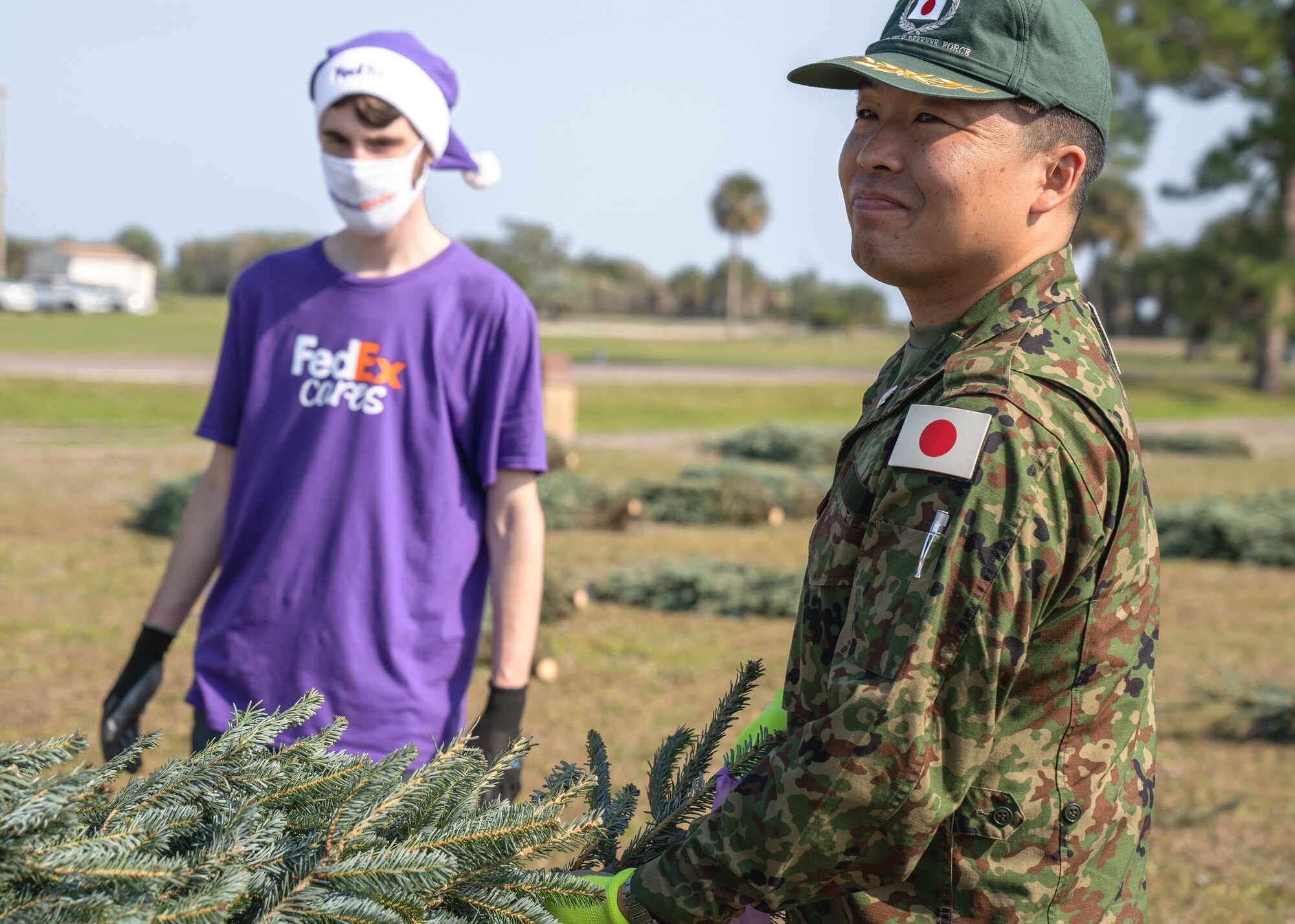 A member of the Japanese Self-Defense Forces picks up a Christmas tree during the Trees for Troops holiday event at MacDill Air Force Base, Florida, Dec. 9, 2021.