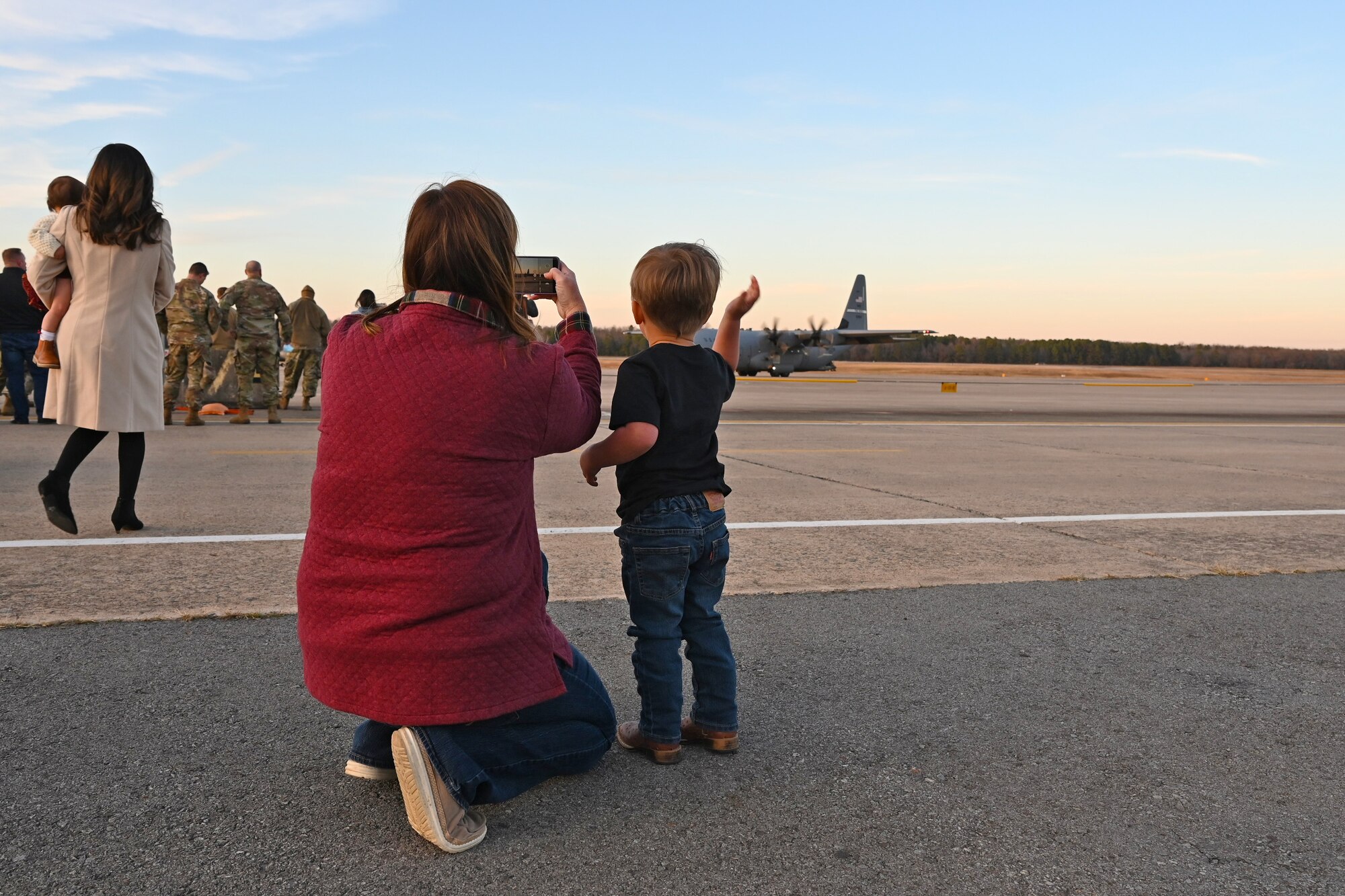 An Airmen's wife takes a picture of the plane returning from deployment.