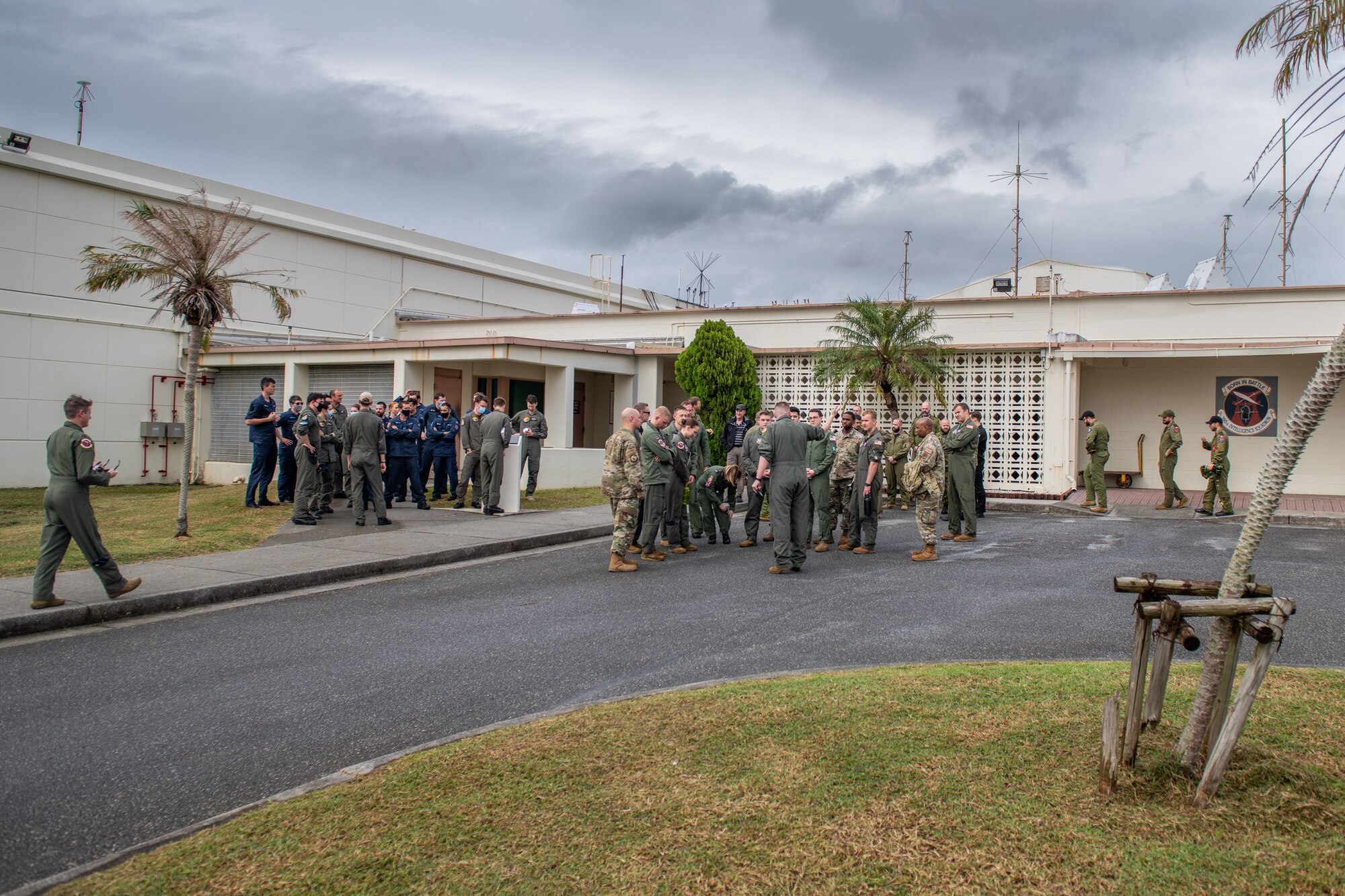 A group of military members from the U.S., New Zealand and Canada gather in front of a building