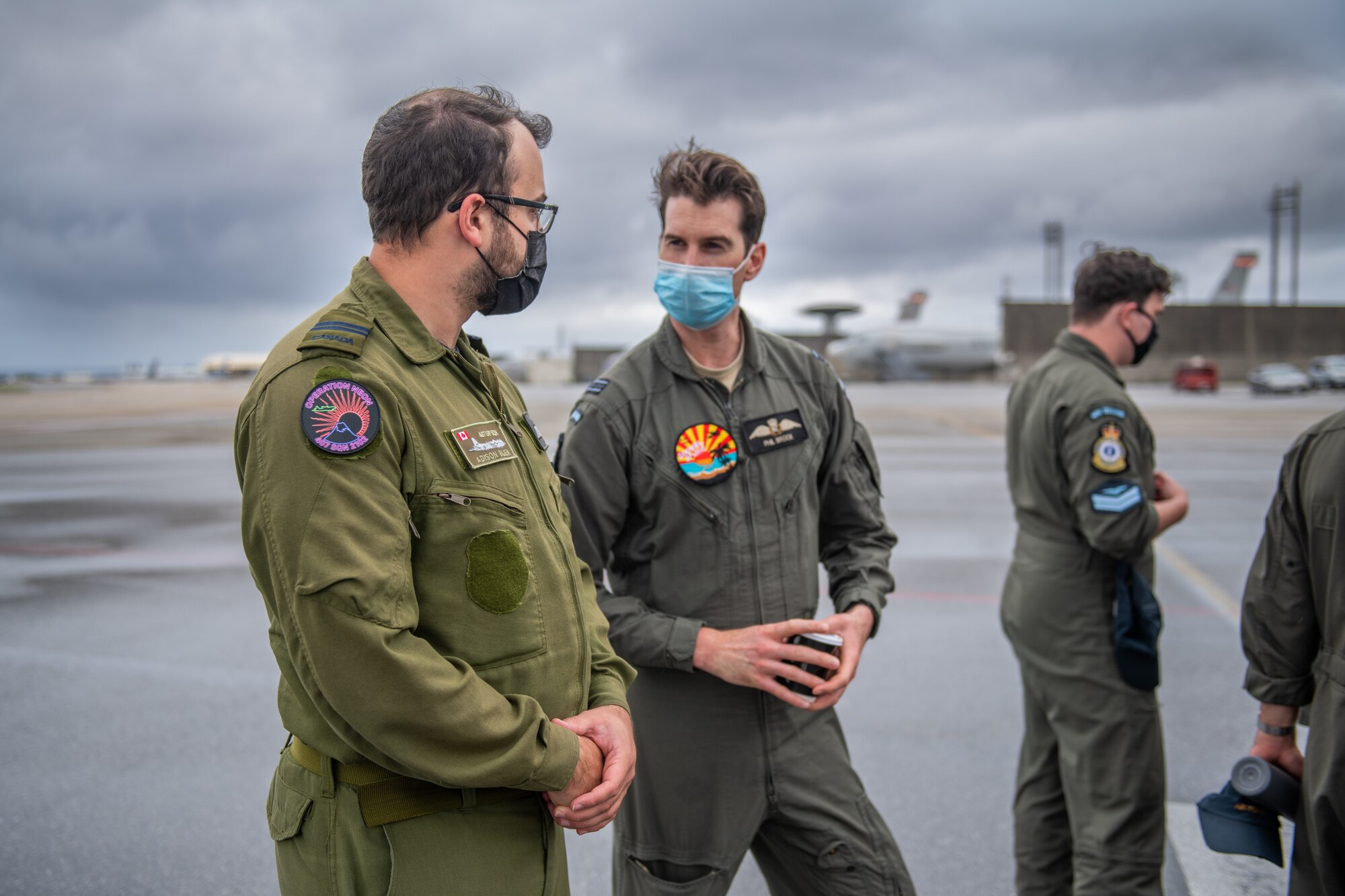 A Canadian and New Zealand military member talk on the flight line