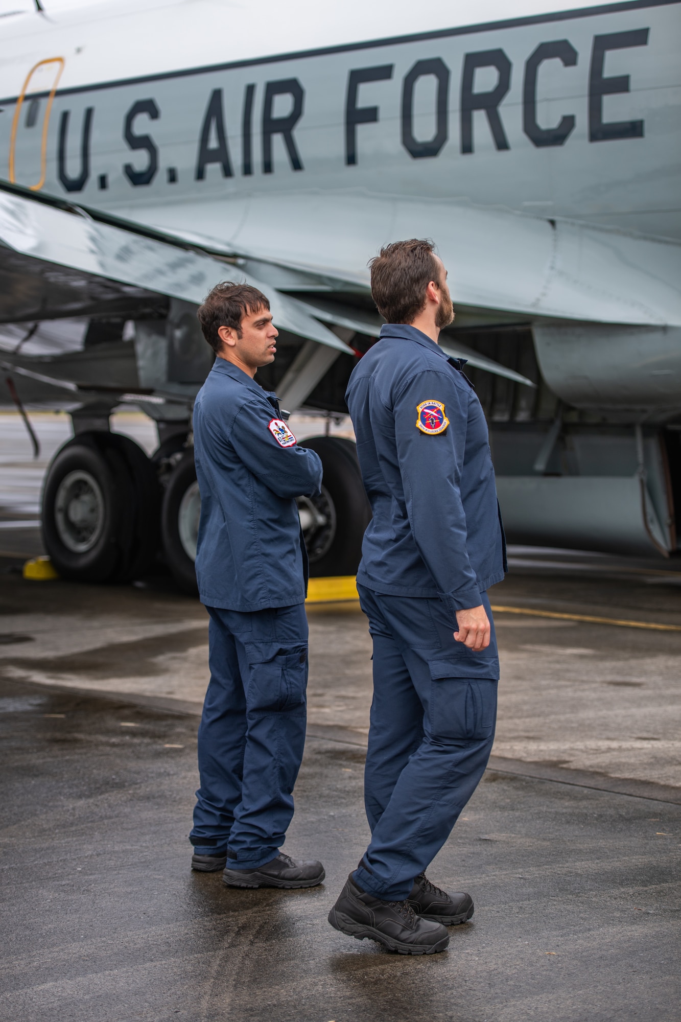 Two military members from New Zealand observe a U.S. Air Force plane