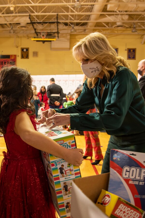 First Lady of the United States Jill Biden, presents a toy to a child at a Toys for Tots event at Joint Base Myer-Henderson Hall, Arlington, Va. Dec. 10, 2021. The U.S. Marine Corps Reserve Toys for Tots Program was founded in 1947 by Maj. Bill Hendricks, USMCR. Since 1947, Marine Reserve Centers throughout the country have collected new, unwrapped toys and distributed those toys to less fortunate children during the holiday season. Presently, the program distributes an average of 18 million toys to 7 million children annually. (U.S. Marine Corps photo by Lance Cpl. Samwel Tabancay)