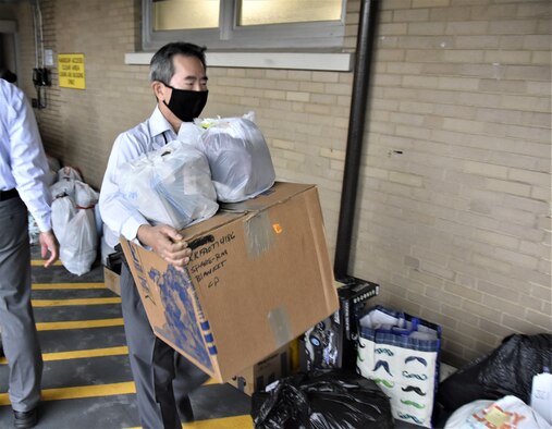 Arnold Engineering Development Complex team member Susumu Cherrix carries gifts Dec. 6, 2021, purchased by Arnold Air Force Base personnel during the 2021 Angel Tree drive from storage in the former barber shop at Arnold AFB to a nearby loading dock. From there, the gifts were loaded for transport off the base to be wrapped and readied for distribution. The workforce at Arnold provided Christmas gifts for more than 200 area children during the latest Angel Tree campaign. (U.S. Air Force photo by Bradley Hicks)