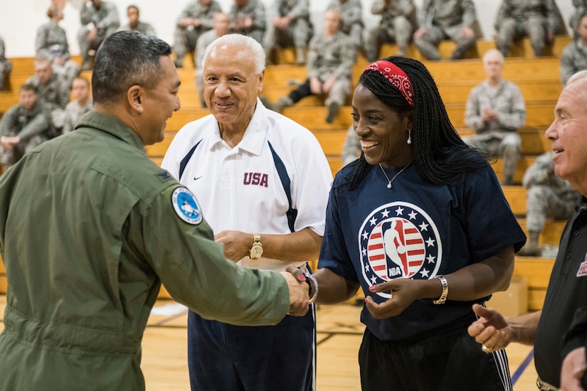 A military commander hands out challenge coins to a woman and two men.