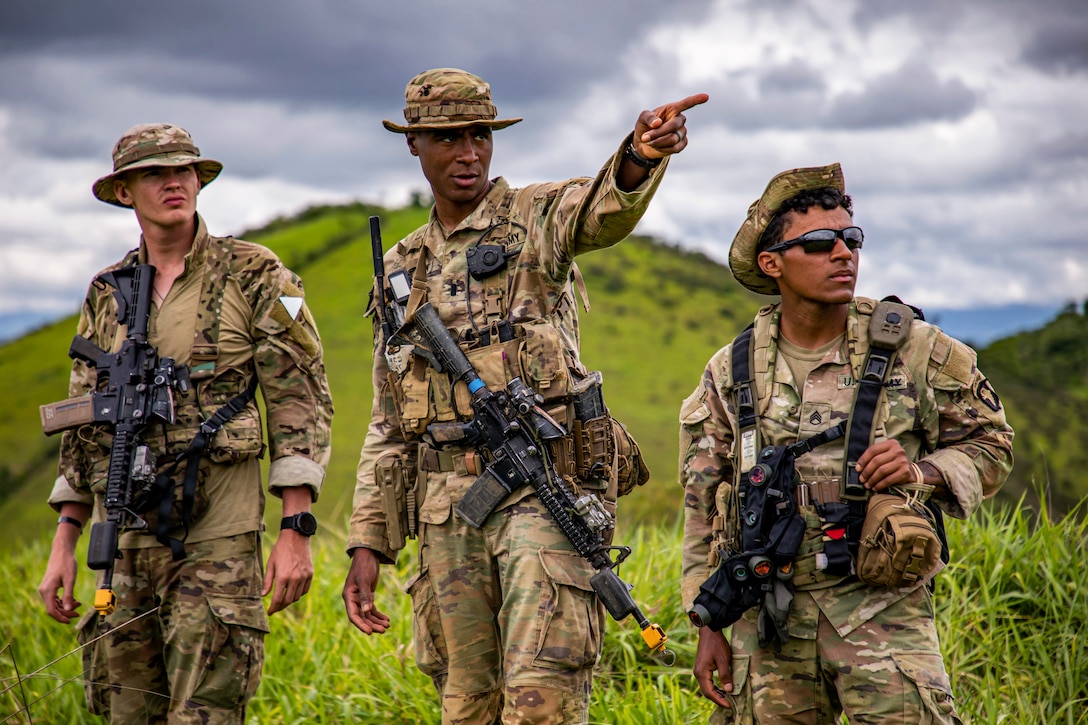 Three soldiers stand next to each other in a field.