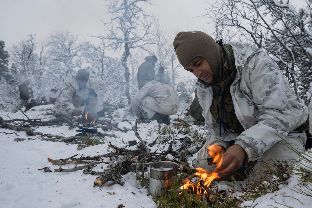 Marines boil snow in a snowy field.