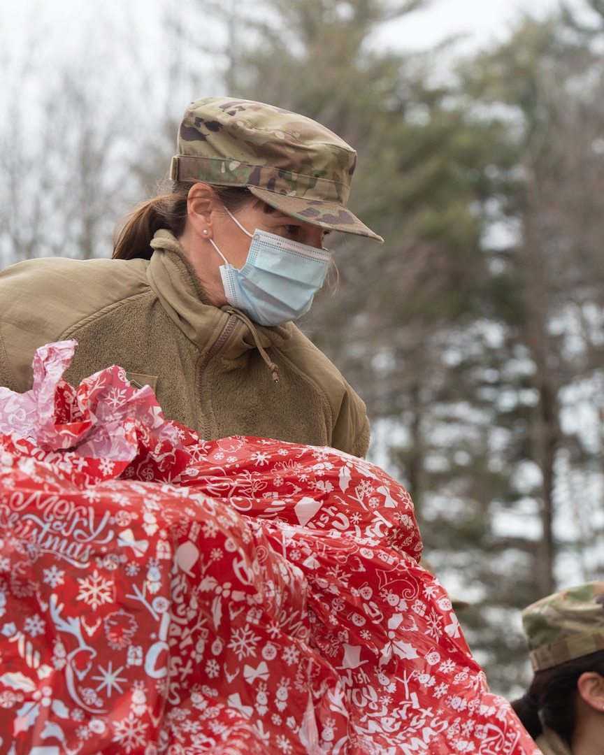 New Hampshire National Guard Master Sgt. Bonnie Demers, an aircrew flight equipment member with the 157th Operations Group, passes a present down a line of Guardsmen at the Portsmouth Department of Health and Human Services Dec. 13, 2021, in Portsmouth, New Hampshire. The Guard partnered with the State Employees Association and Department of Health and Human Services to send holiday gifts to nearly 3,000 children.