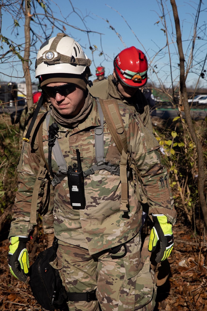 Airmen and soldiers comb through wreckage left by a tornado.