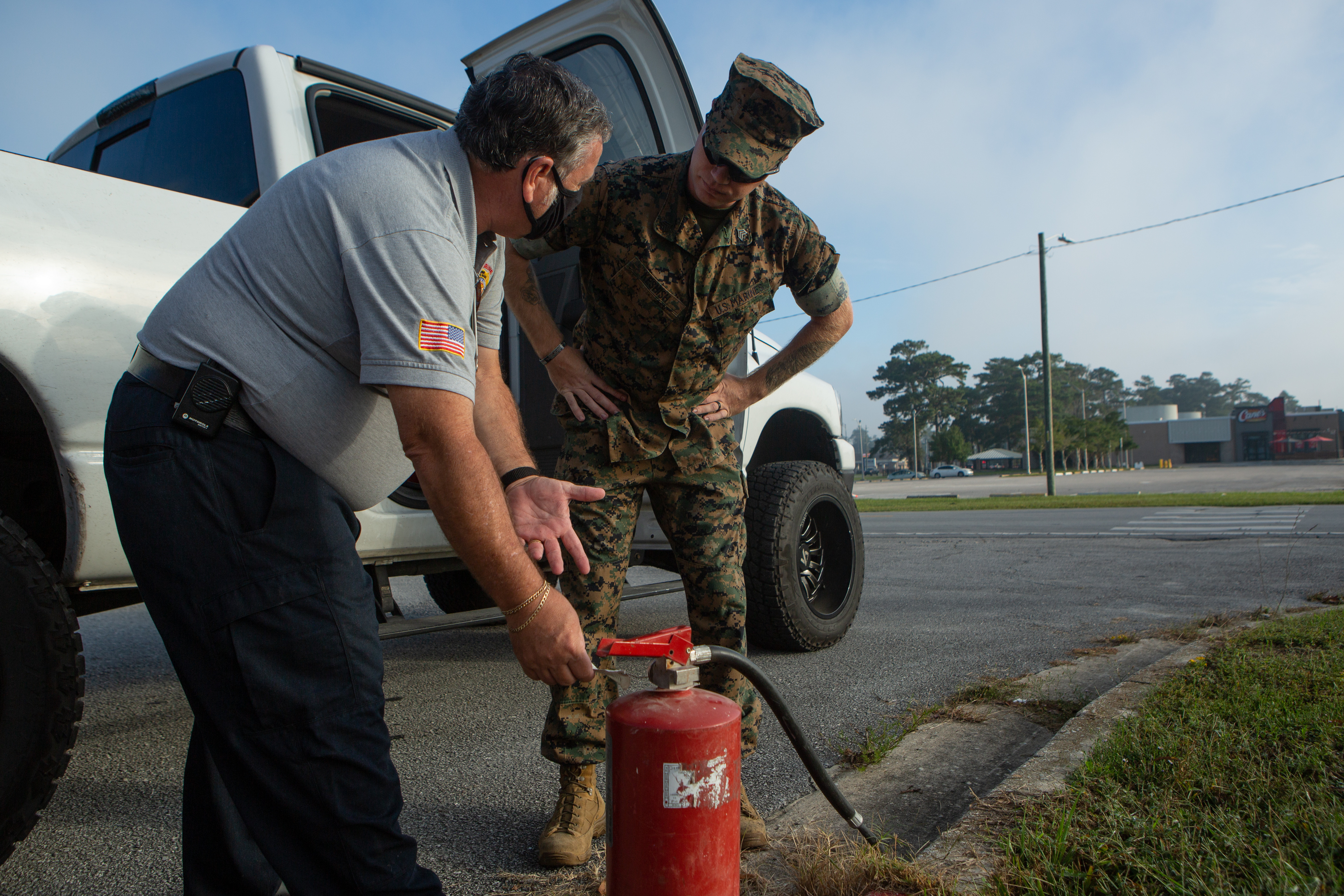 A man and a marine working with a fire extinguisher outside.