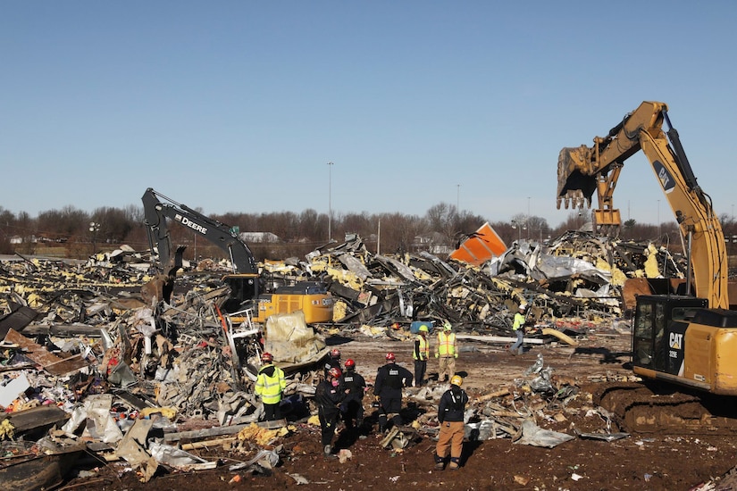 Military and civilian workers sift through debris.