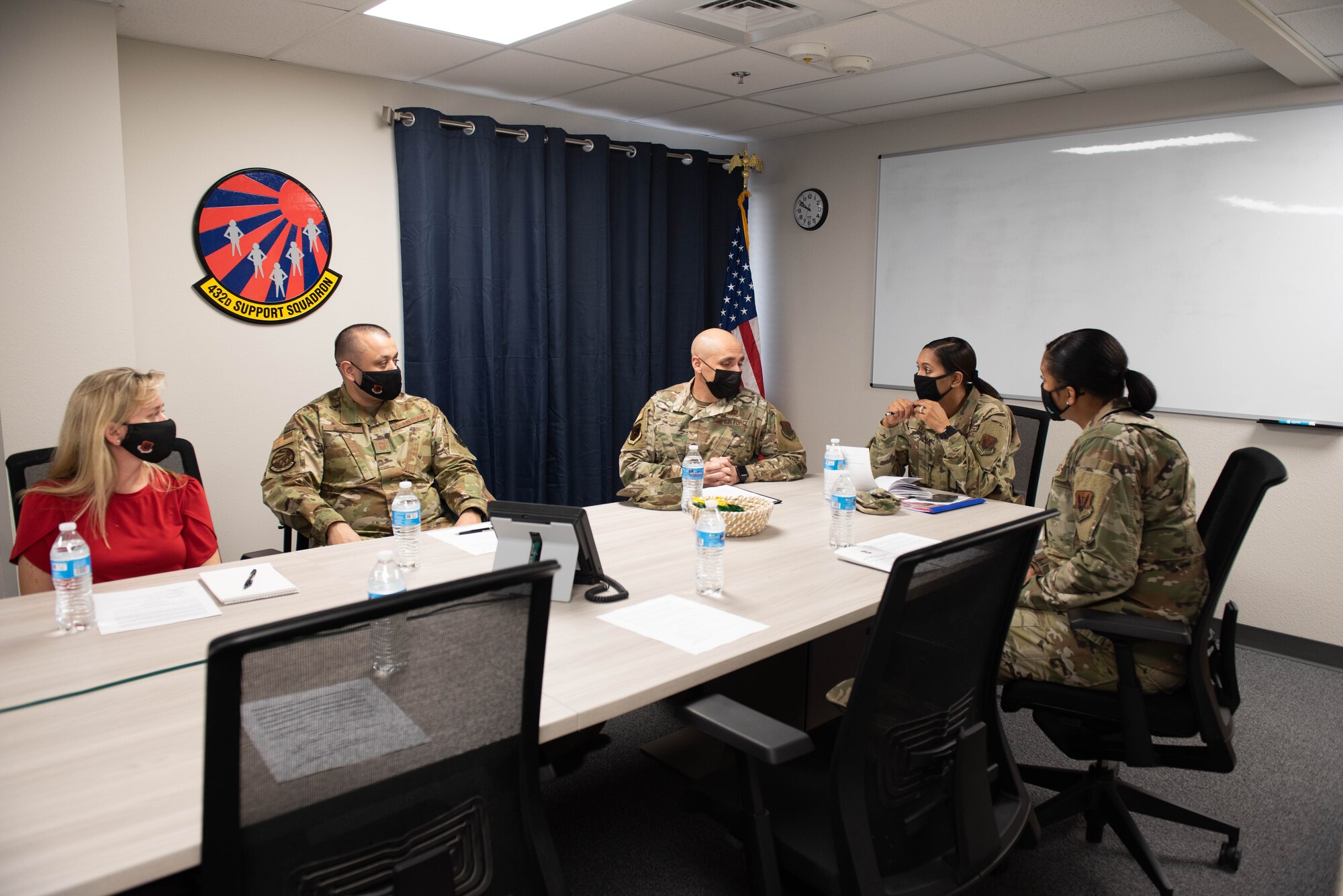 Airmen assigned to the 432d Support Squadron, brief Chief Master Sgt. Sonia T. Lee around a conference table.