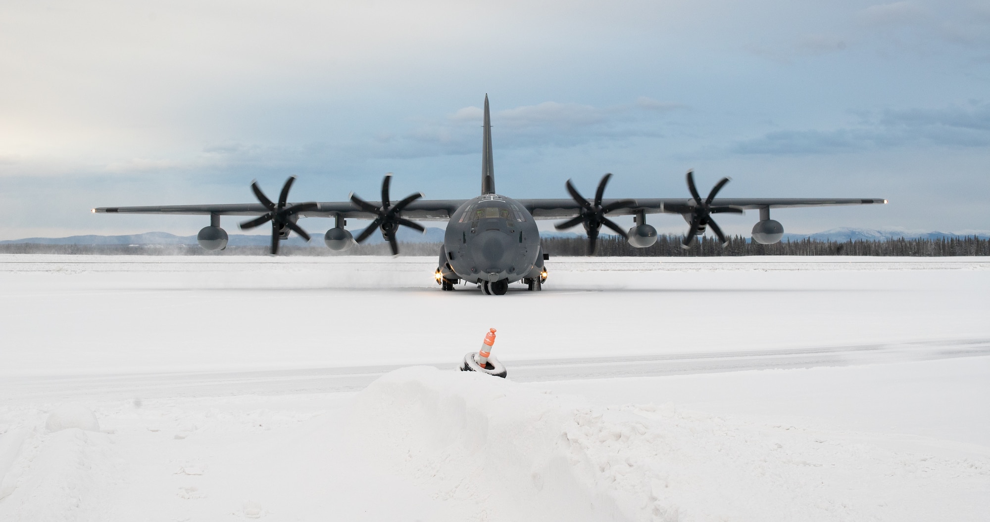 A C-130 sits on a snowy runway.